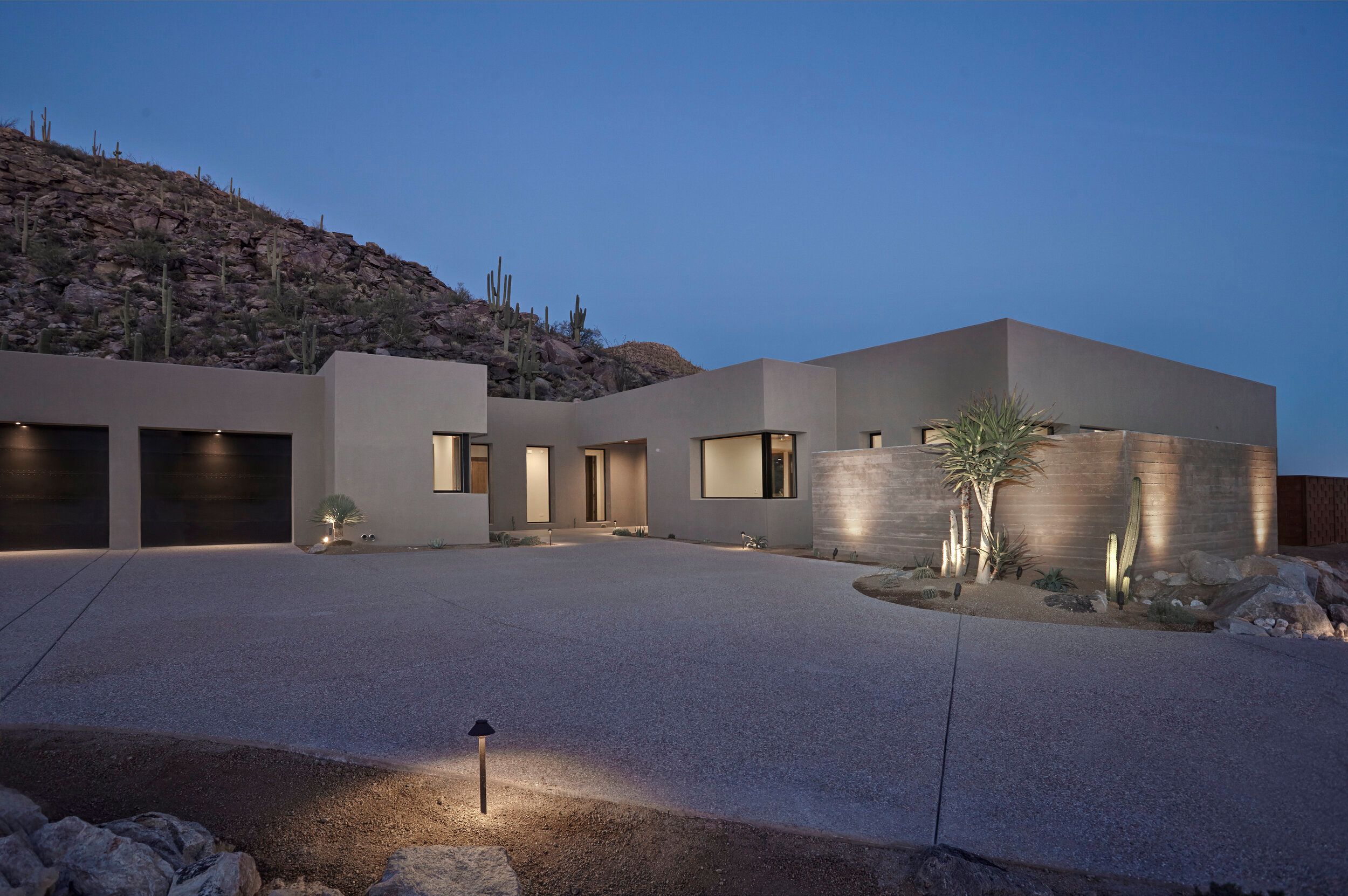 Front elevation at twilight with garage doors and a concrete motor court