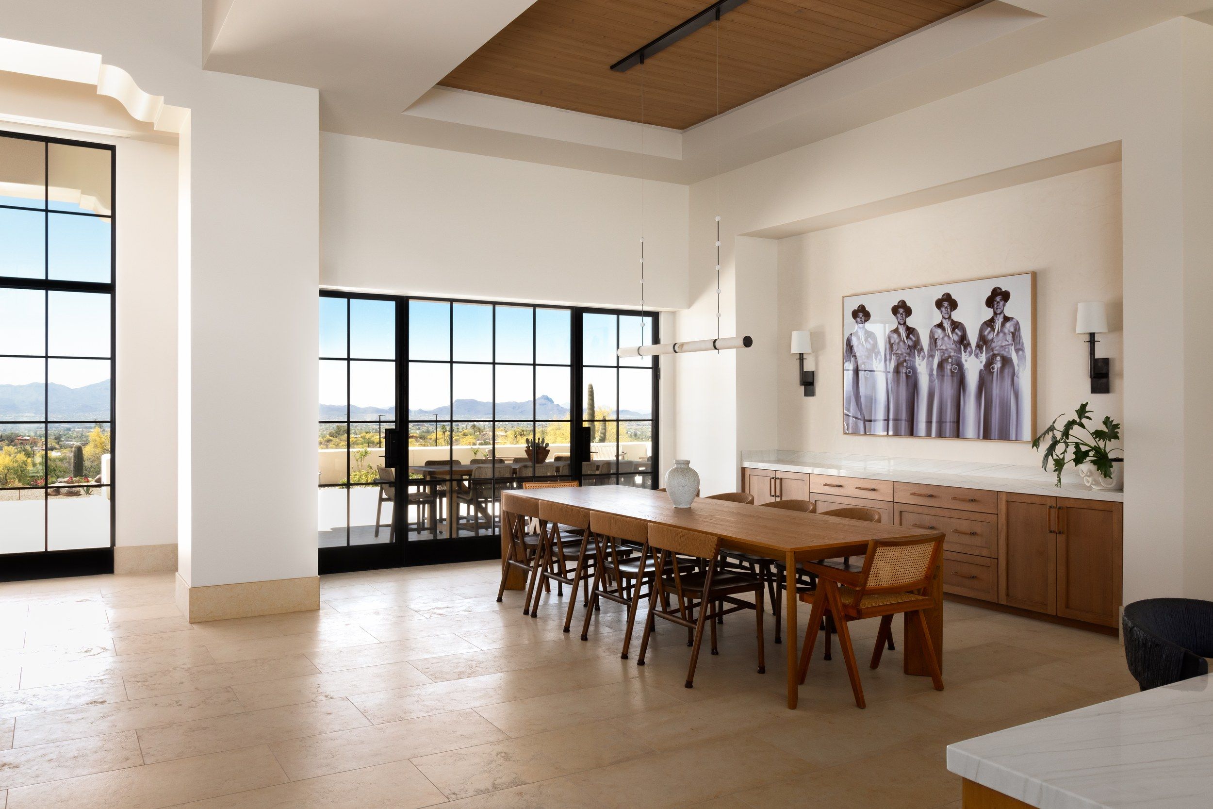 Dining room with a long walnut table, steel-framed windows and a mountain view