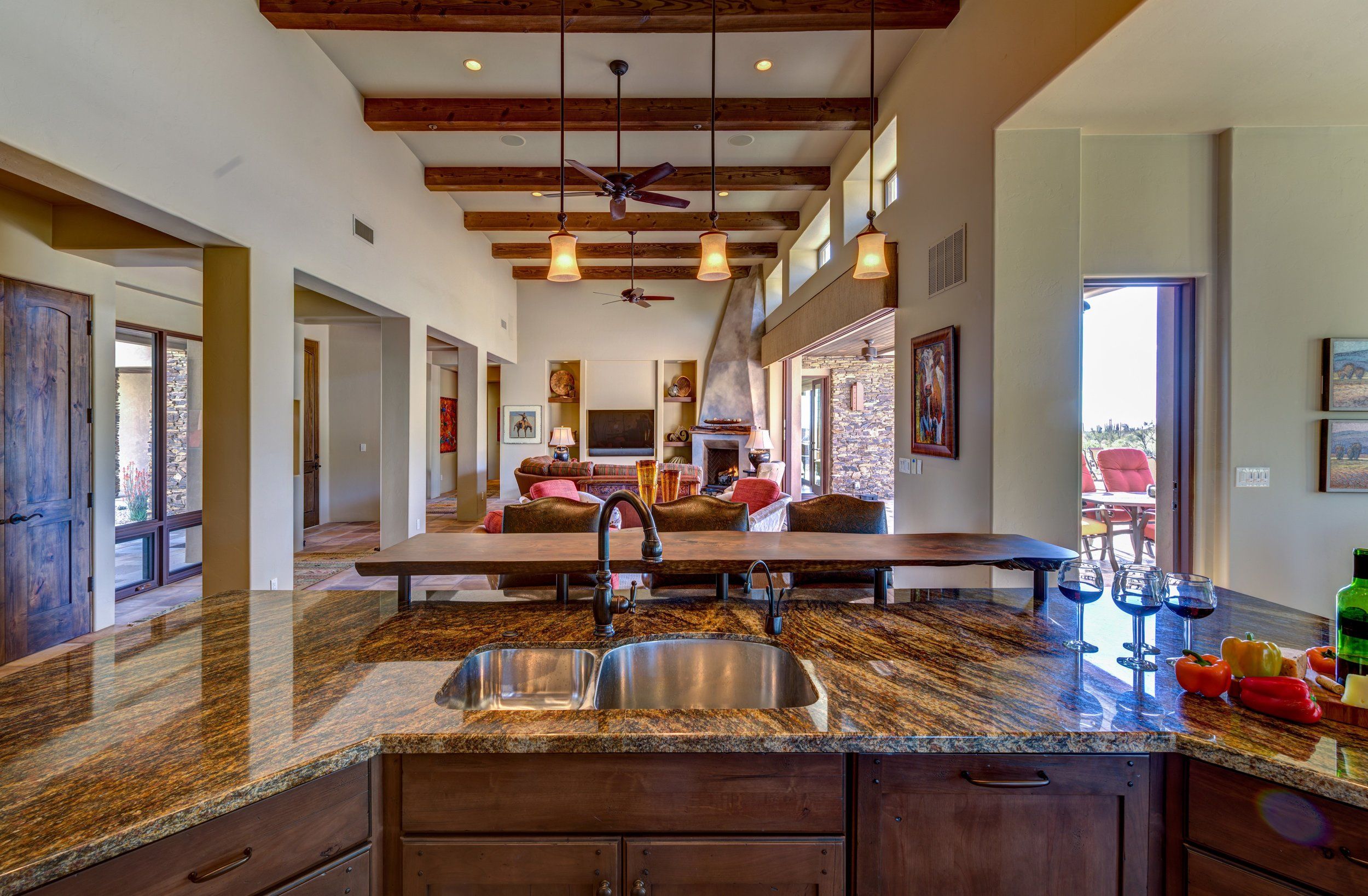 Kitchen island with a granite counter, prep sink and beamed ceiling beyond