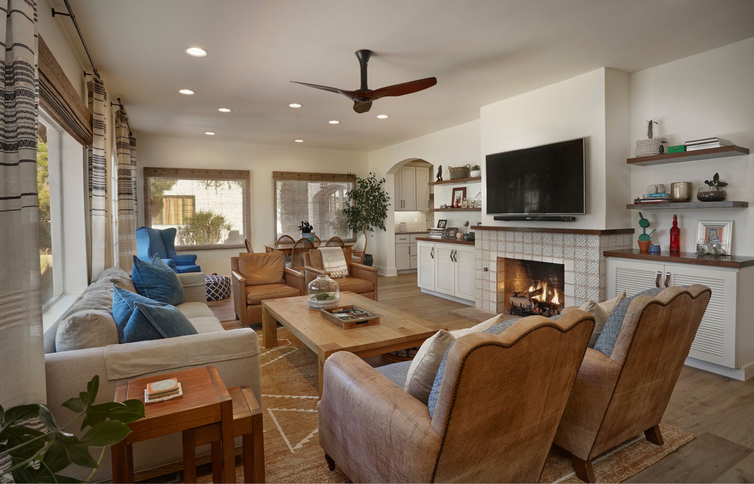 Living room with a white-tiled fireplace, built-in shelving and leather armchairs