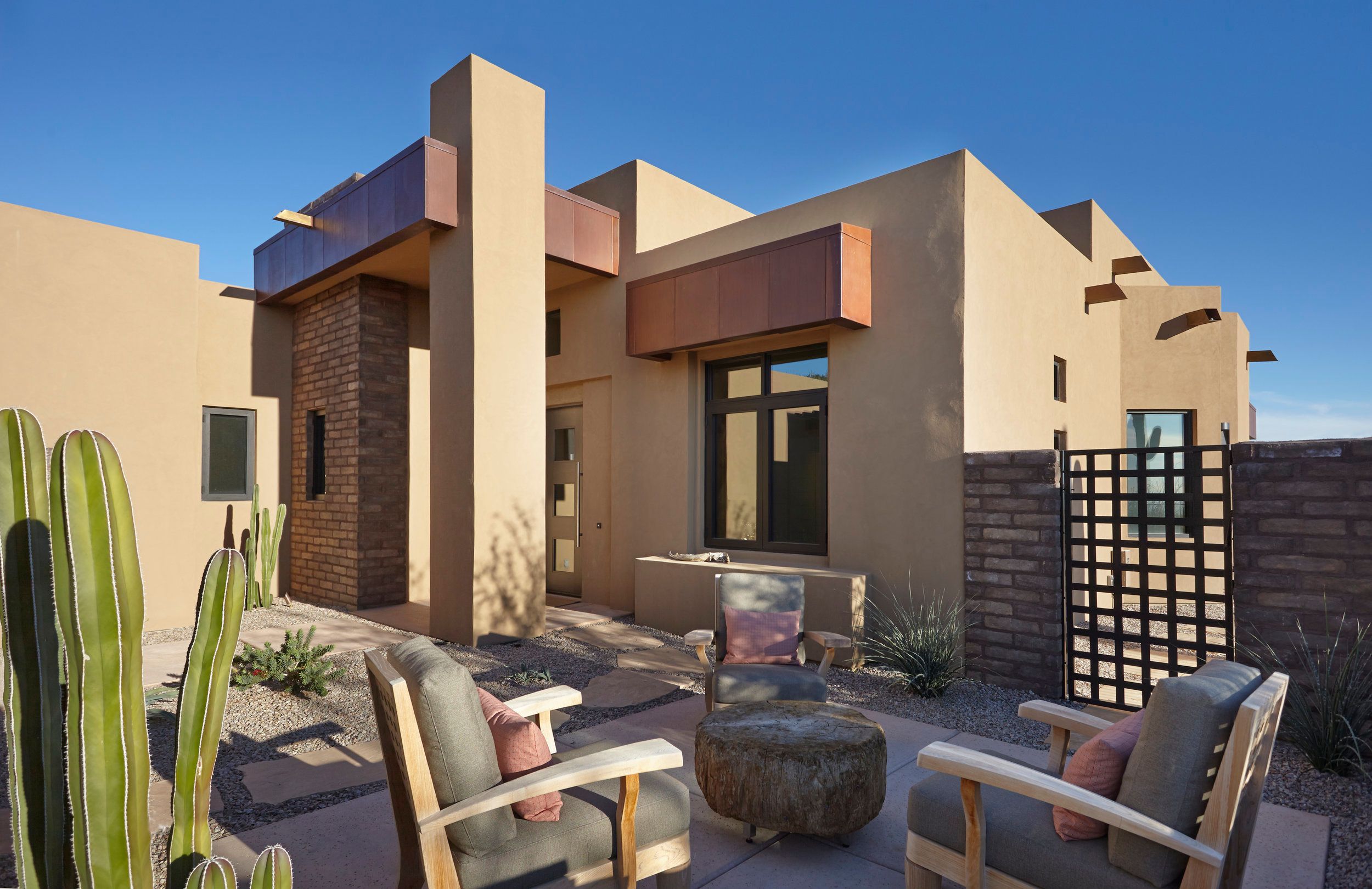 Entry courtyard with lounge chairs, organ pipe cactus and a brick privacy screen