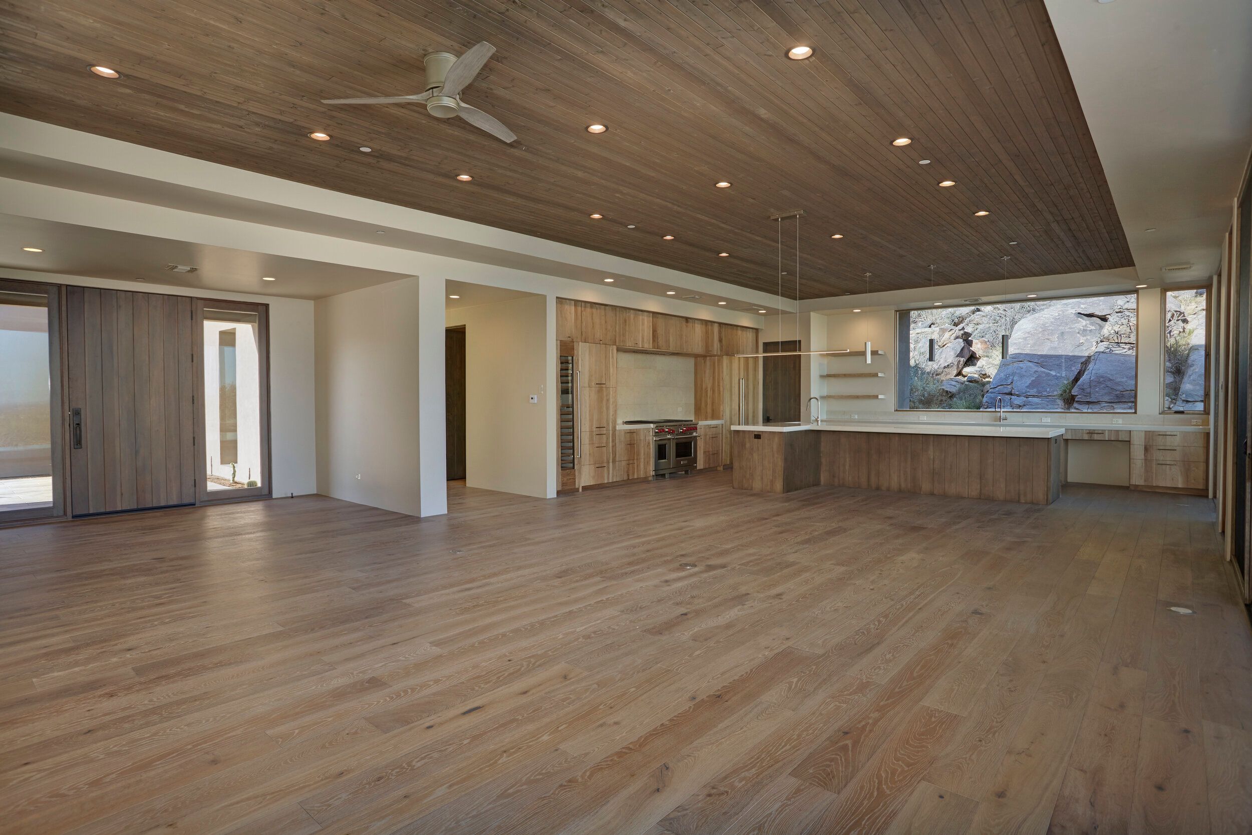 Open great room with a wood-plank ceiling and oak floors before furnishing