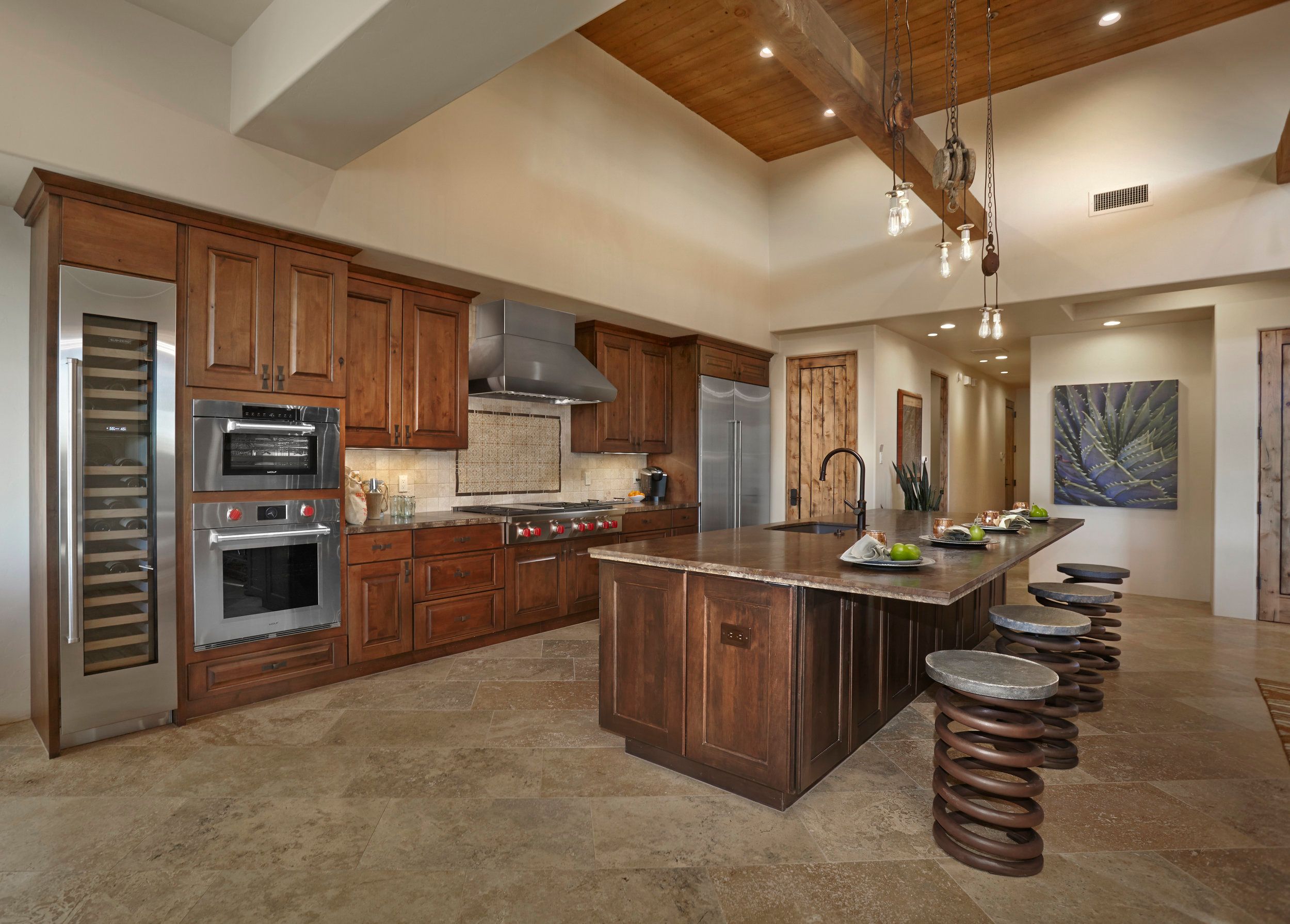 Kitchen with walnut cabinetry, a glass wine wall and stone-topped island
