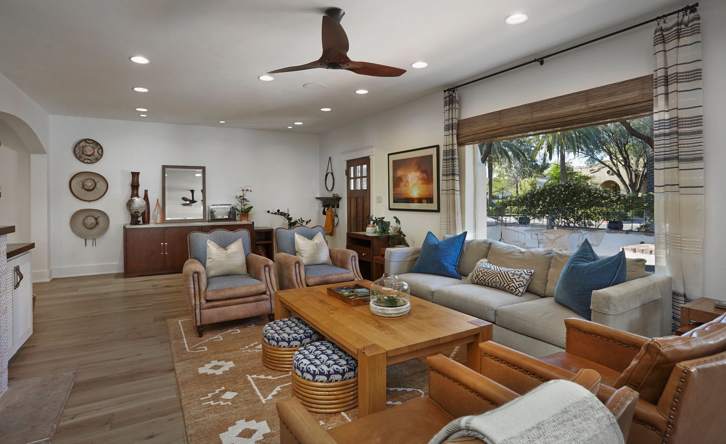 Living room with a sectional sofa, ceiling fan and shuttered windows