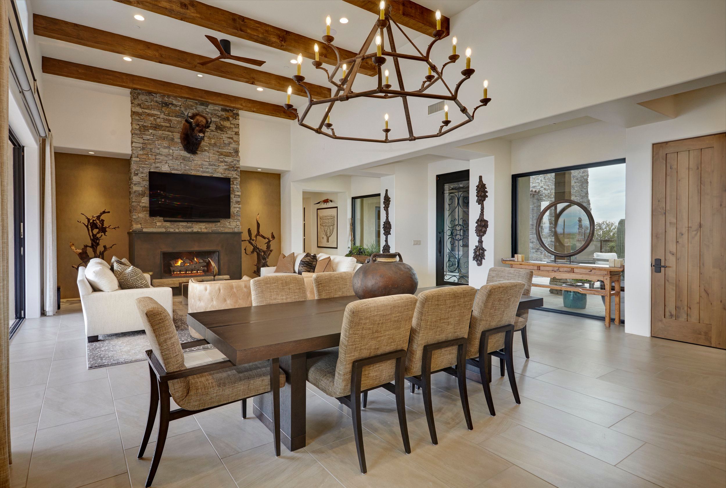 Dining area with a branching iron chandelier and stone fireplace beyond