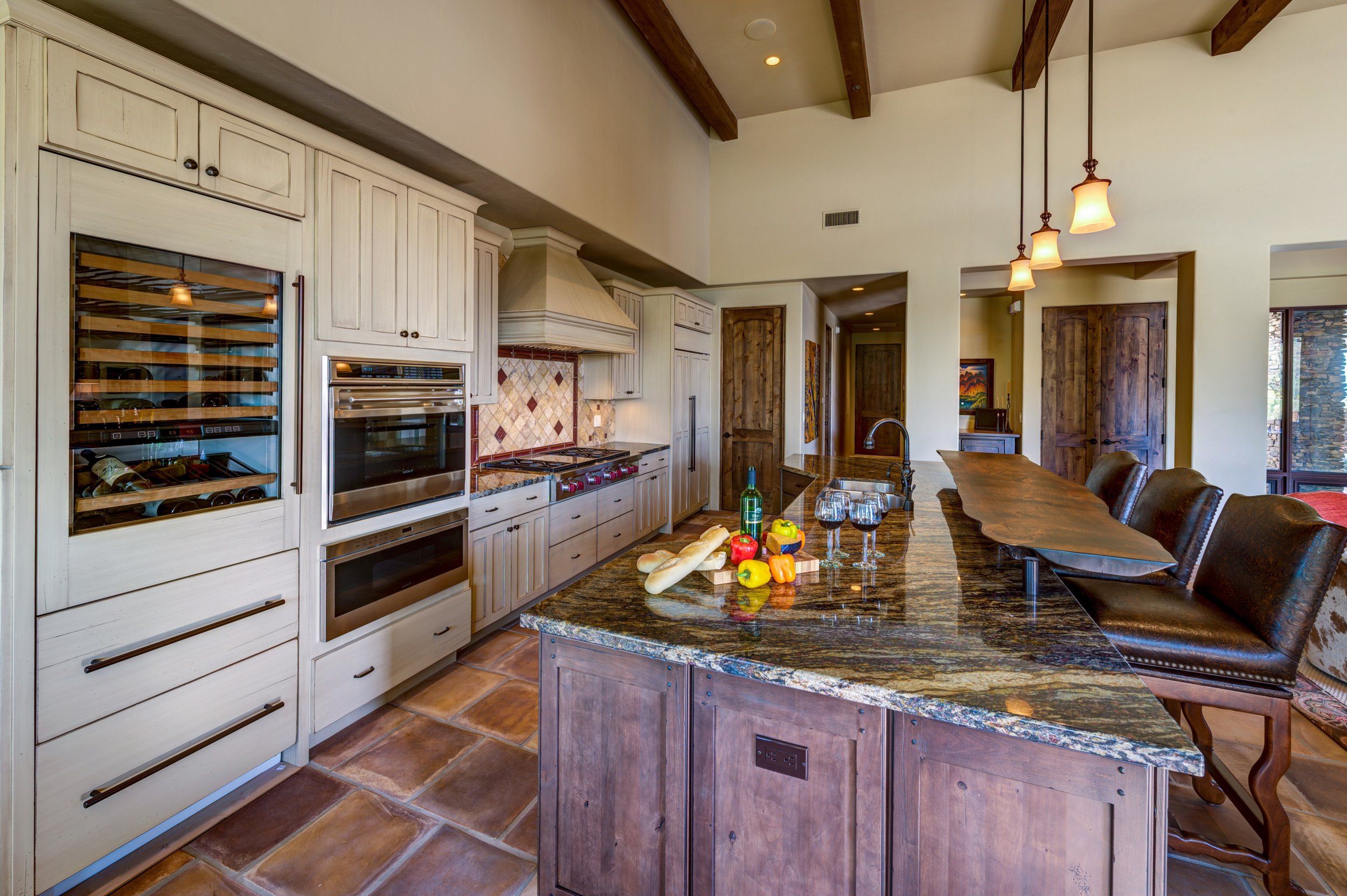 Kitchen with a wine refrigerator, double ovens and a granite island with seating