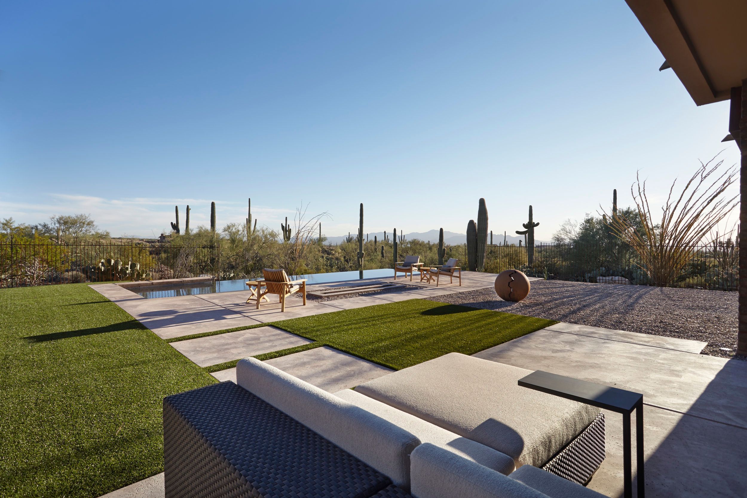 Lawn and negative-edge pool with modern outdoor seating and desert beyond