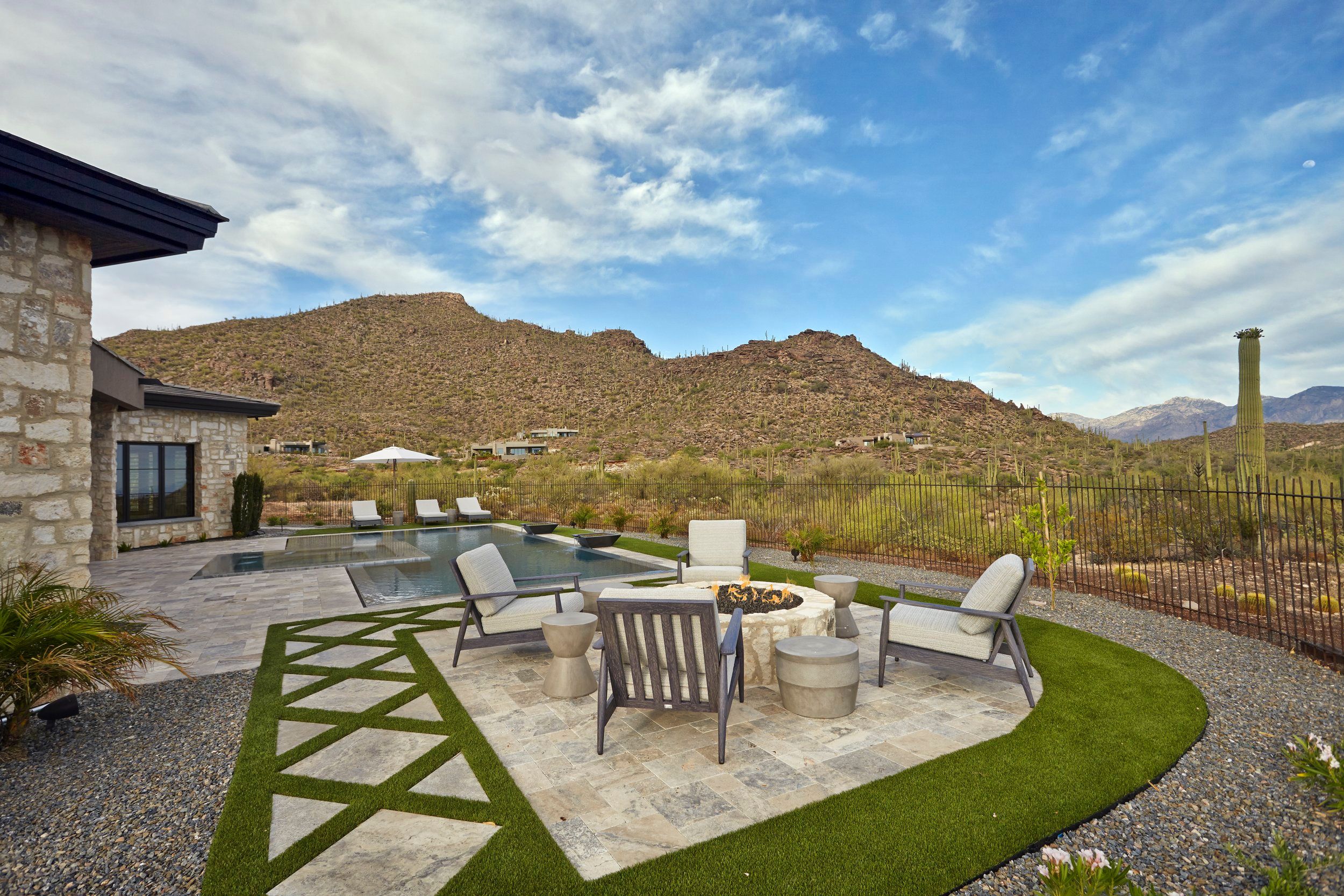 Pool terrace with lounge chairs, a fire pit seating group and mountain backdrop