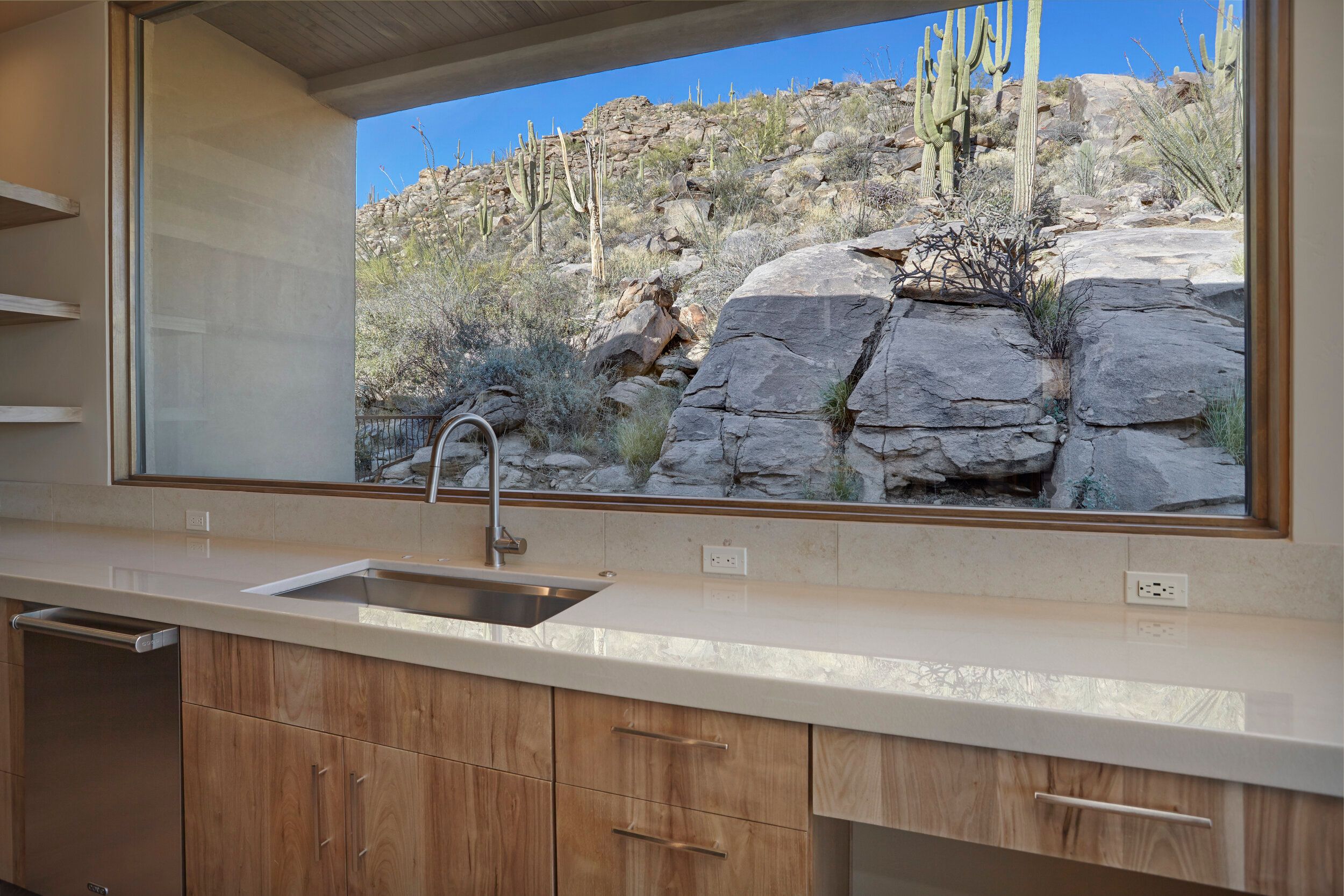 Kitchen sink beneath a picture window framing the boulder outcrop