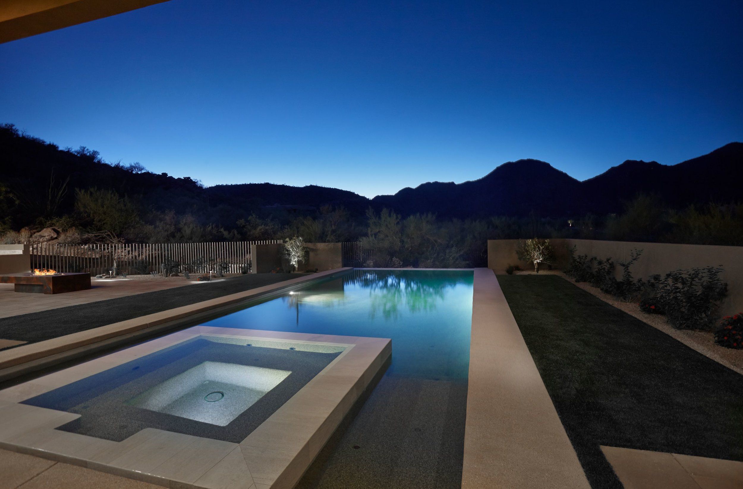 Pool and spa reflecting a deep blue twilight sky with mountains behind