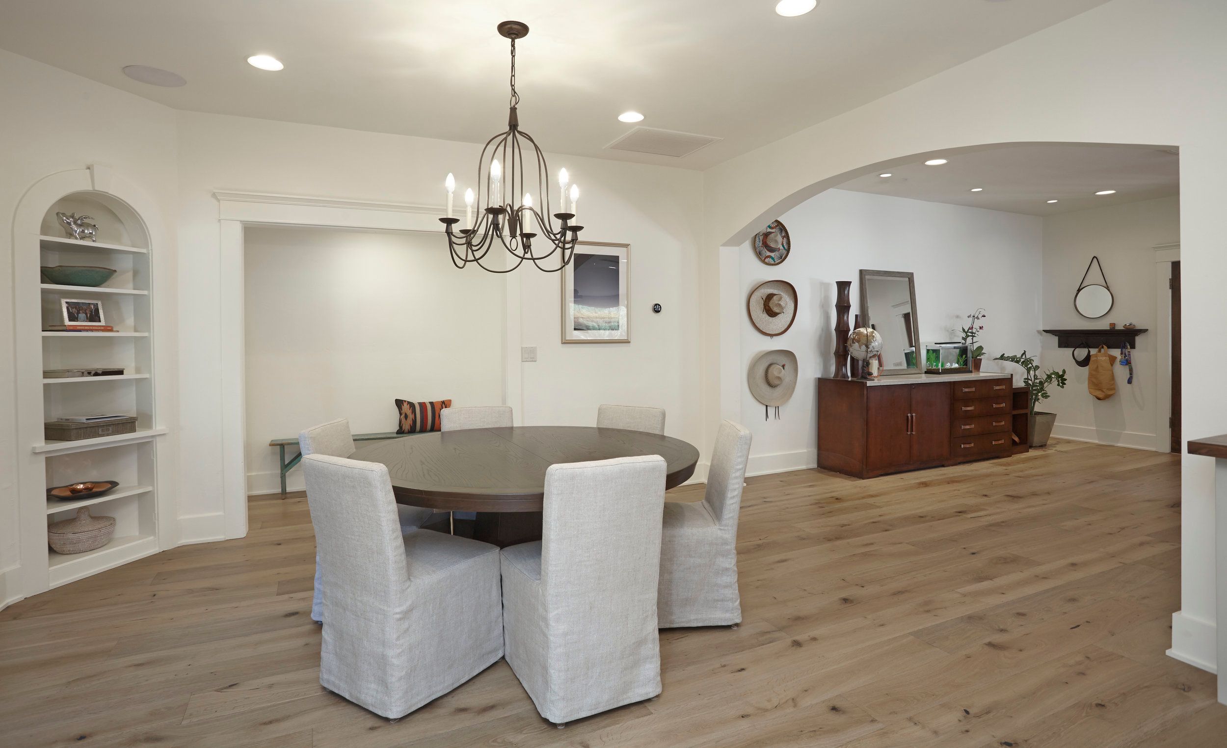 Dining room with an iron chandelier, round table and built-in shelving