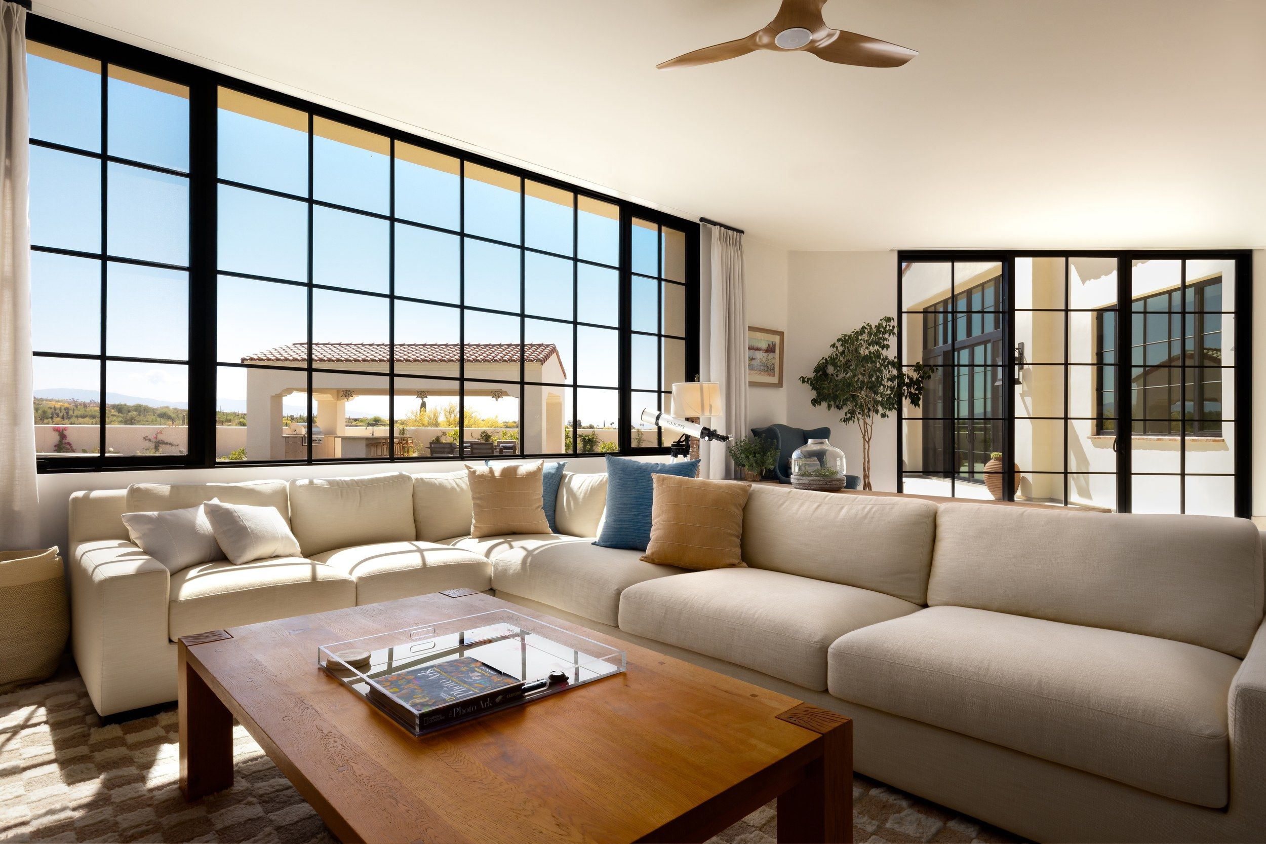 Great room with a long sectional beneath a wall of steel windows