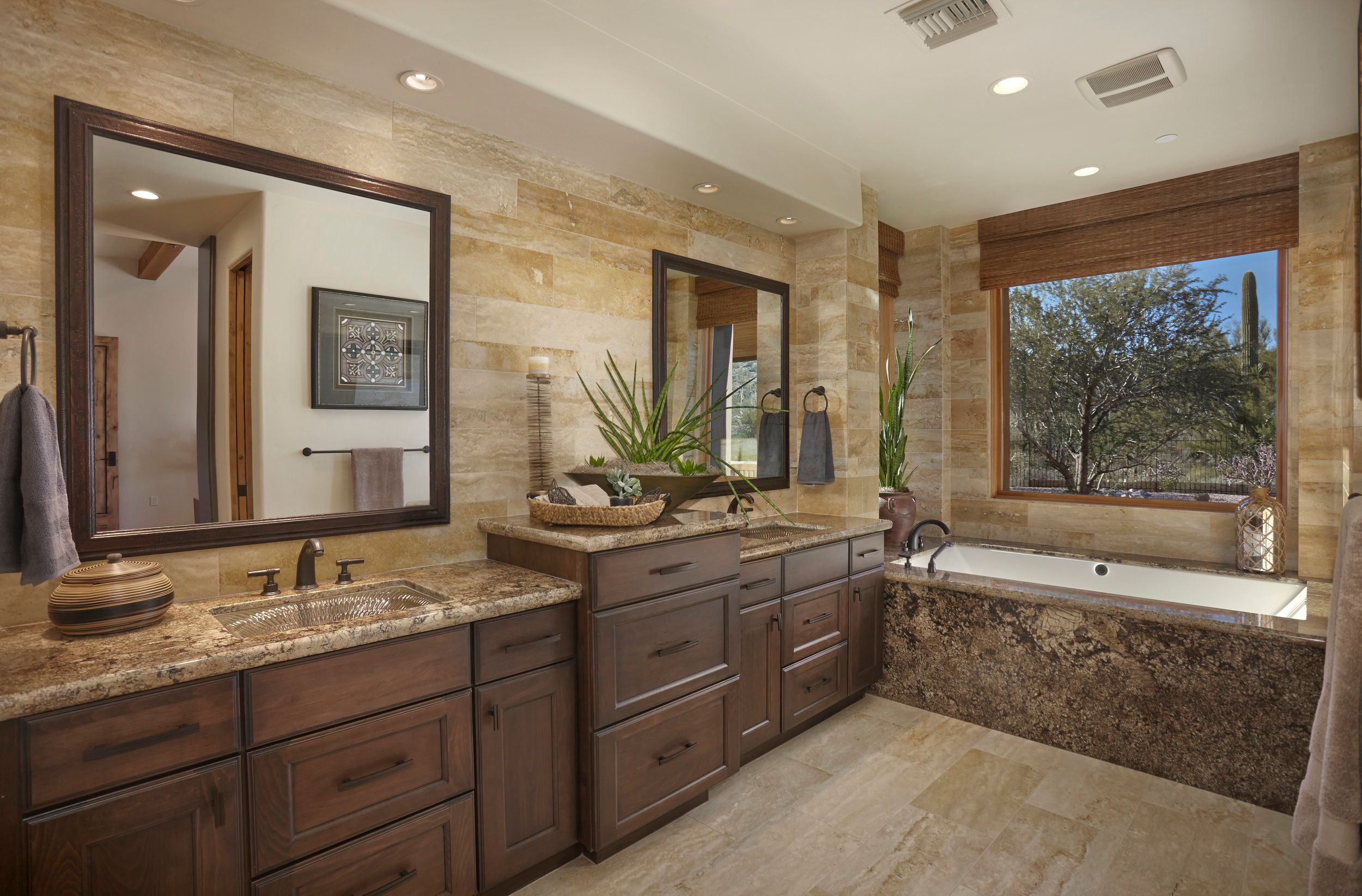 Primary bathroom with twin vanities, framed mirrors and a tub beneath the window