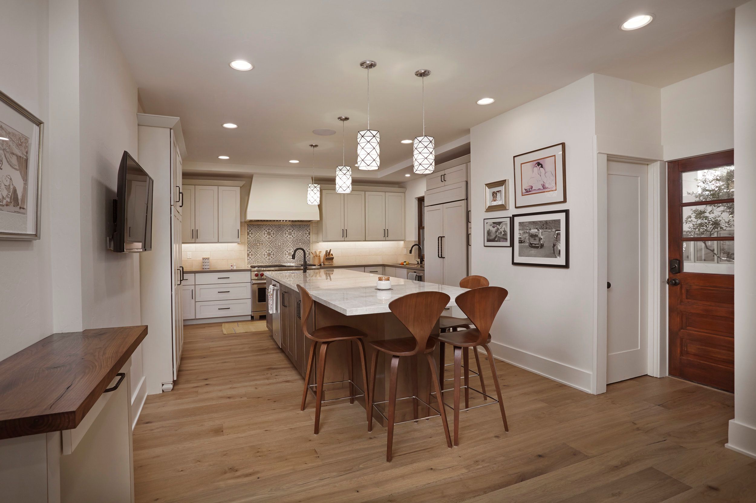 Kitchen with white cabinetry, a walnut counter bar and pendant lights