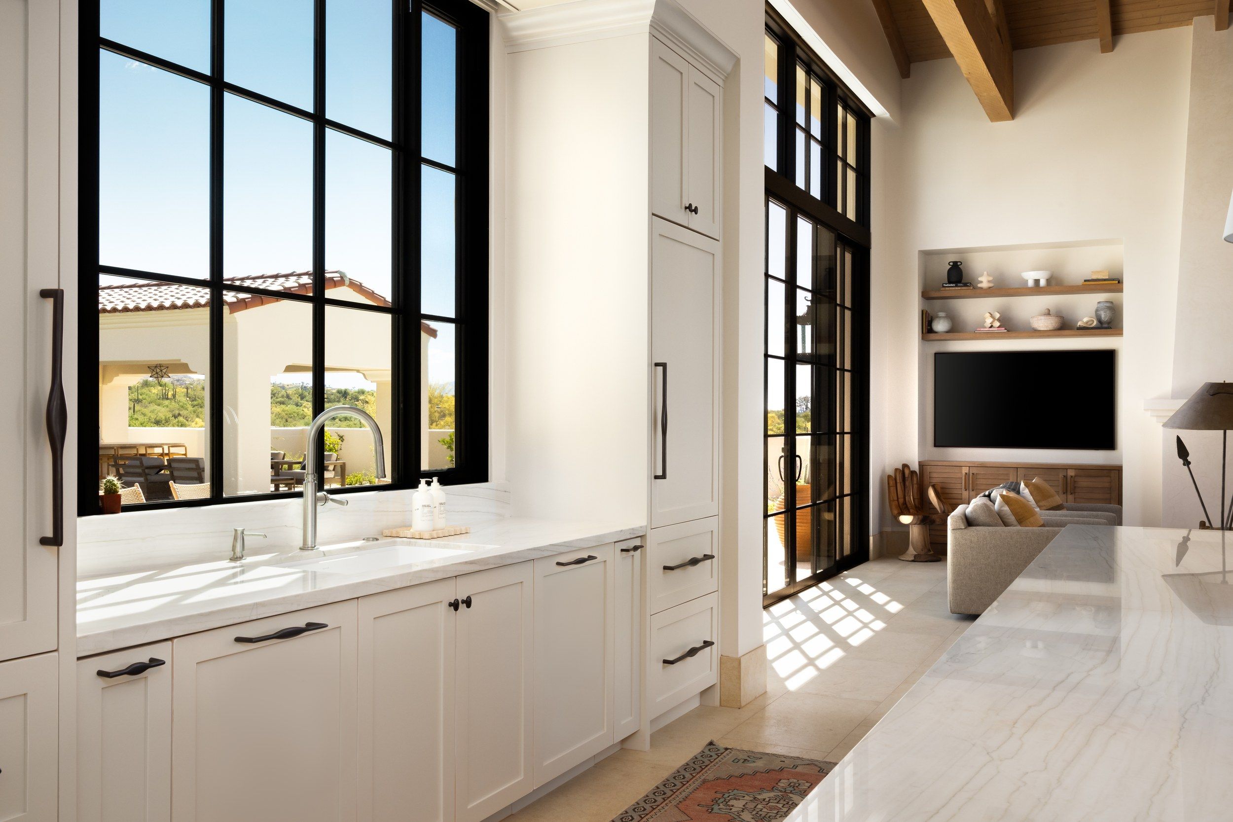 Kitchen with marble counters, black steel windows and a view through to the living room