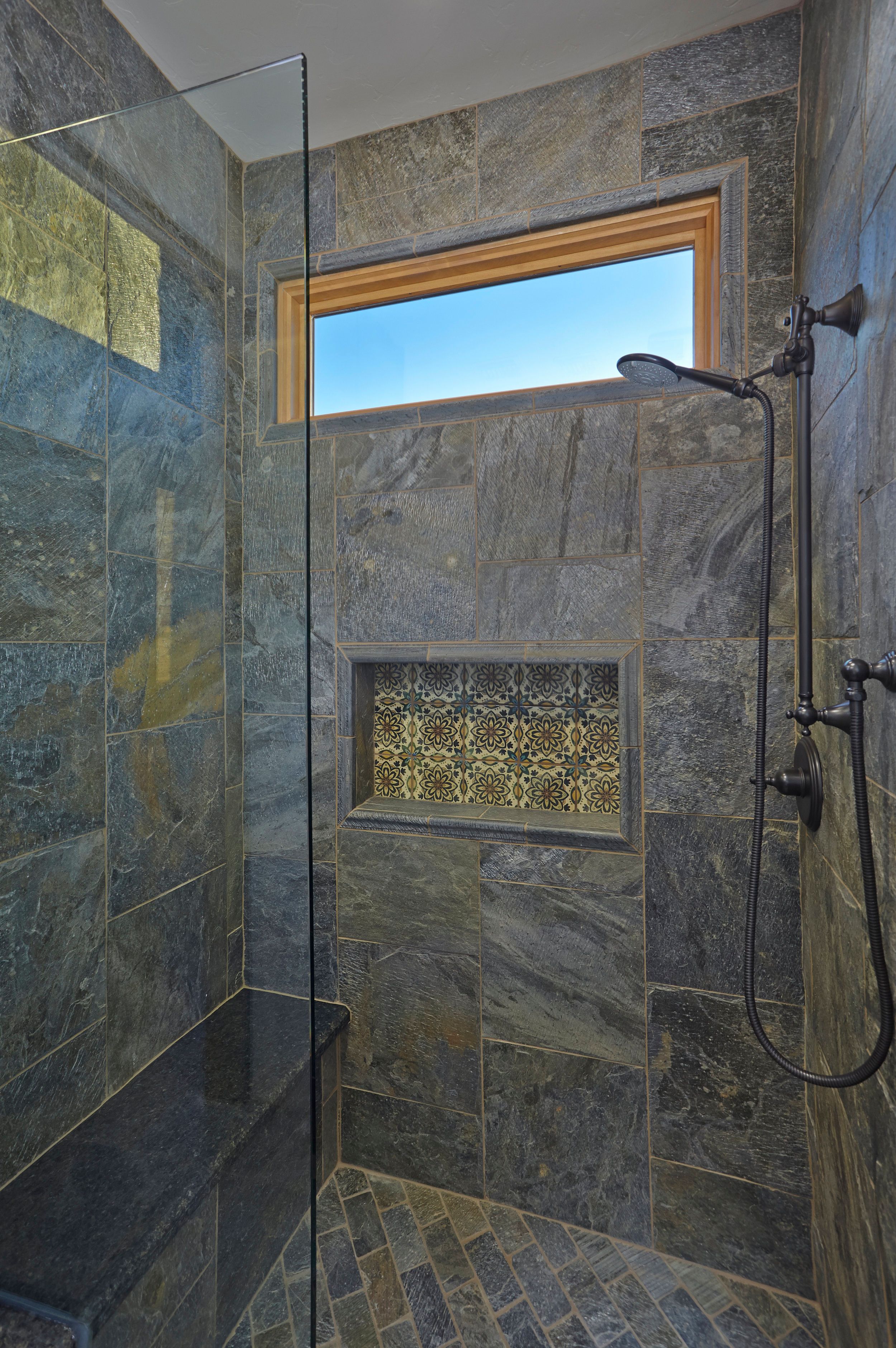 Walk-in slate shower with a rain head and tiled niche