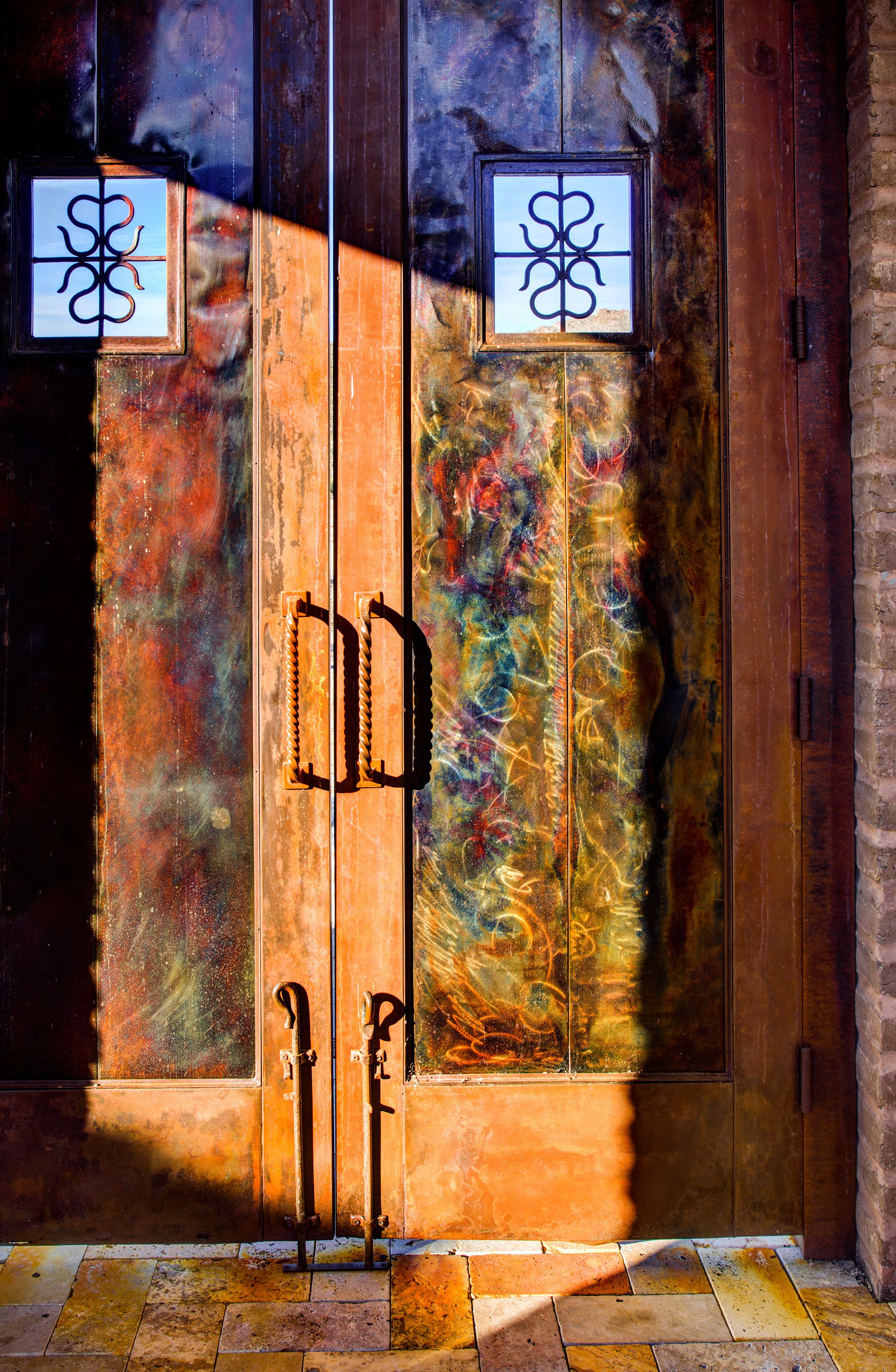 Detail of the copper entry doors with decorative glass panels and iron pull handles