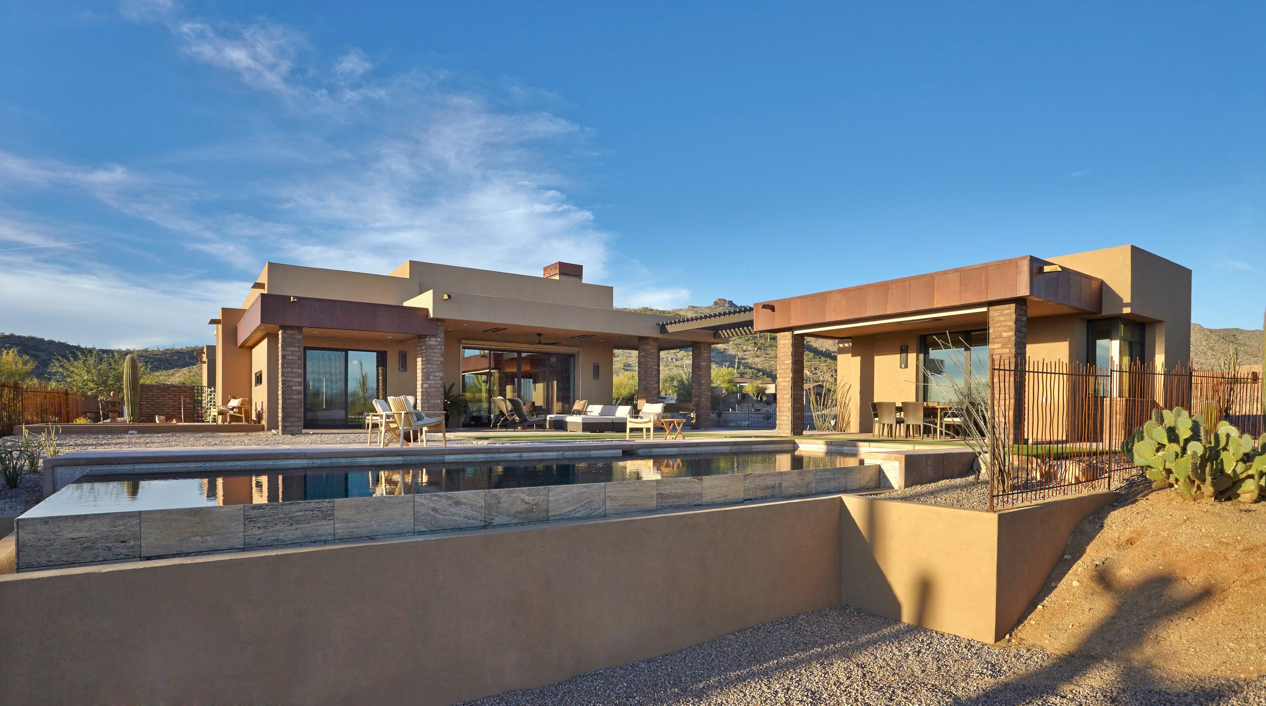 Rear elevation with a corten-clad wing and pool below a clear blue sky