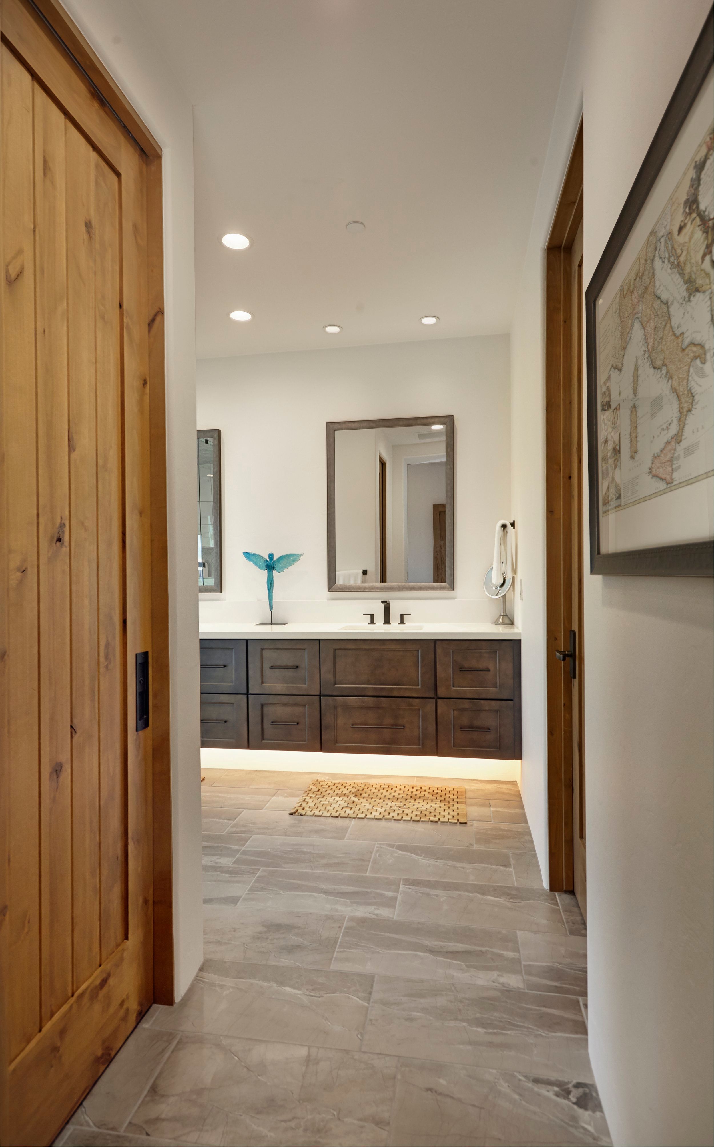 Hallway with a knotty alder door looking through to the bathroom vanity