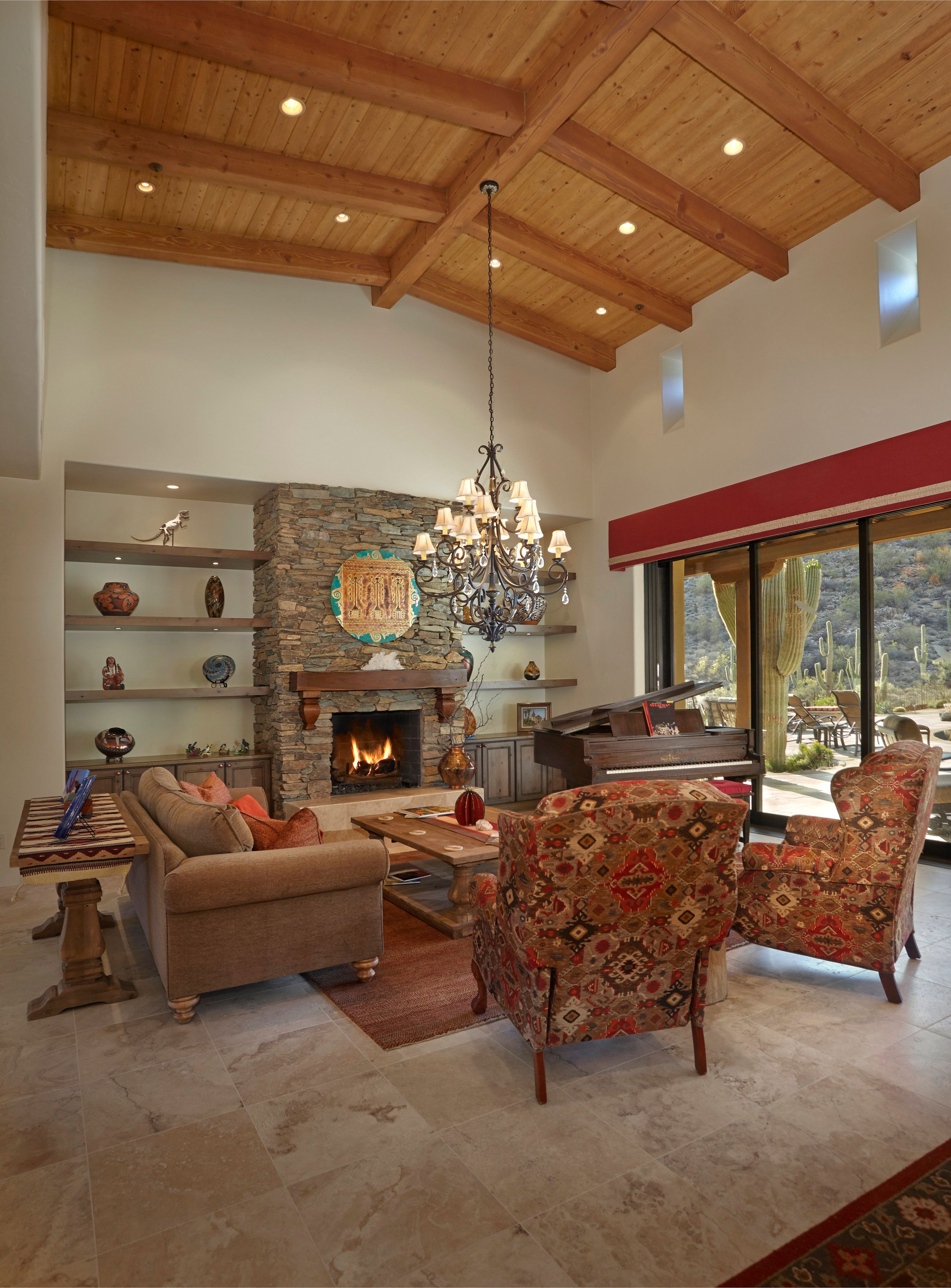 Living room with a stone fireplace, built-in shelving and vaulted wood ceiling