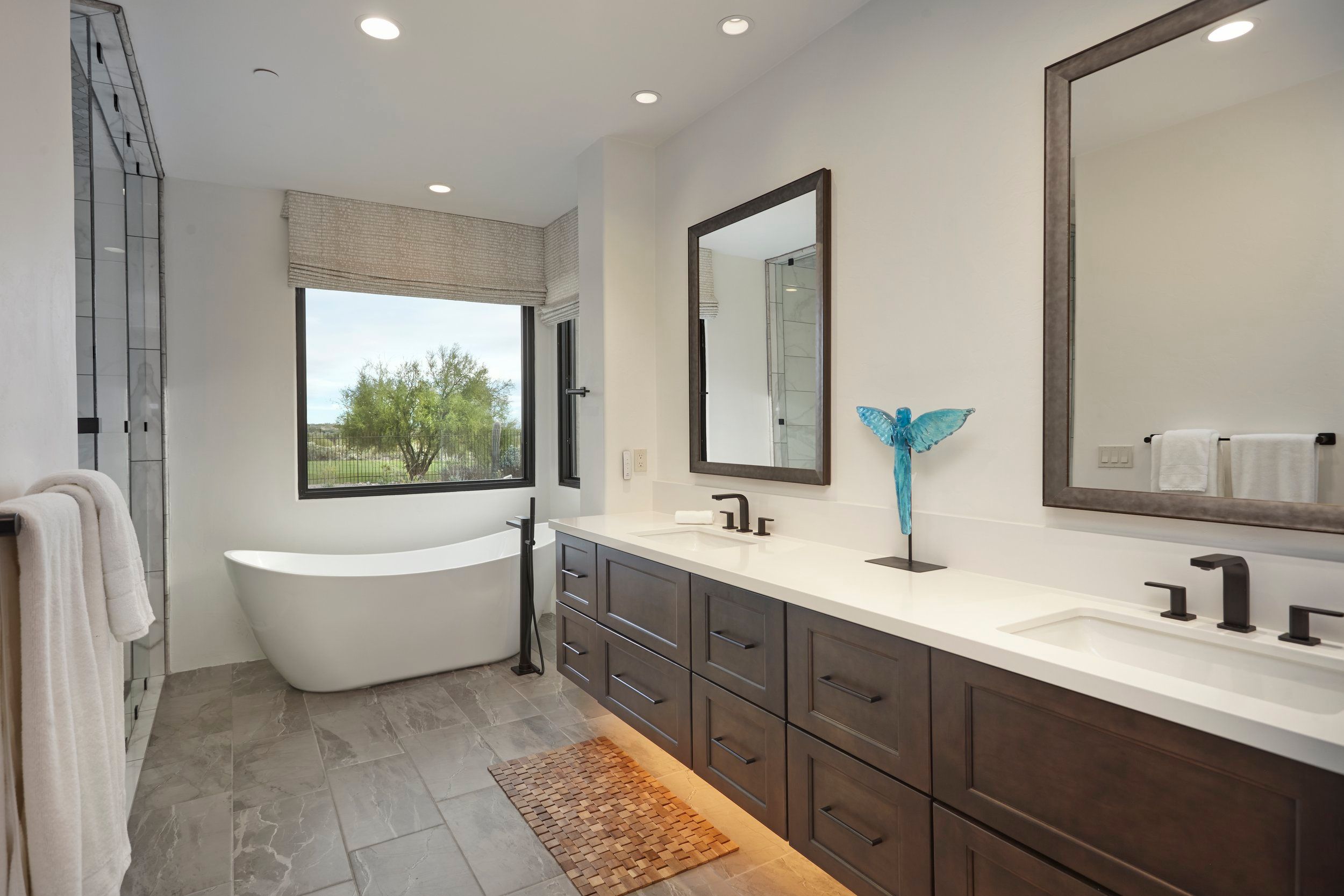 Primary bathroom with a freestanding tub, twin vanities and a desert window