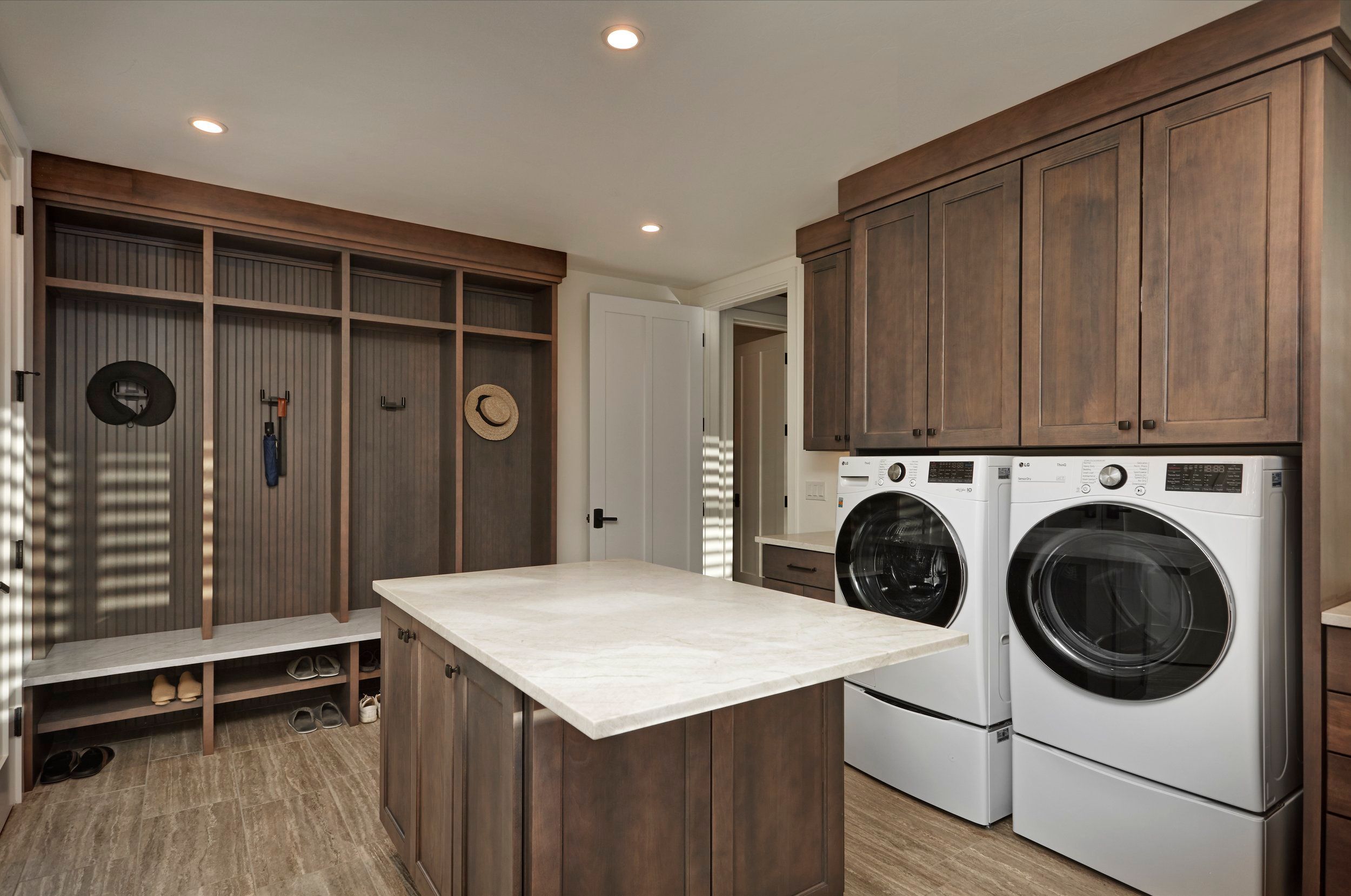 Laundry and mudroom with built-in lockers, a marble-topped island and side-by-side machines