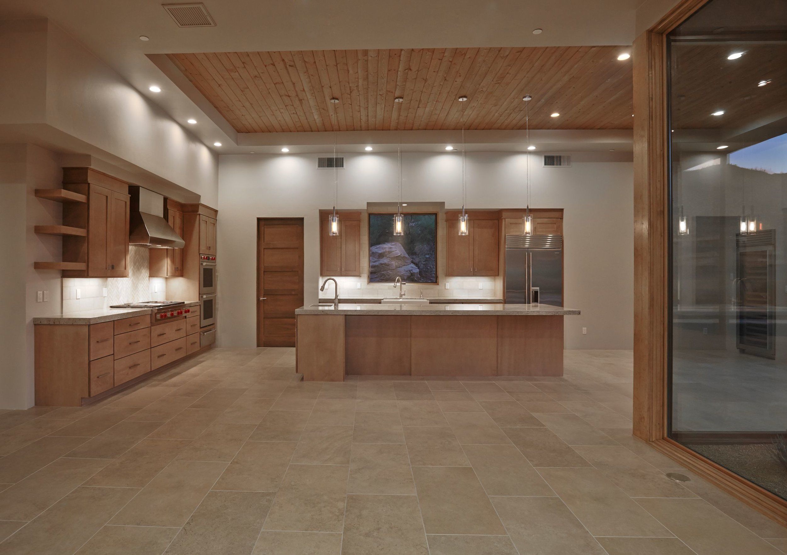 Kitchen with maple cabinetry, a stone island and wood-plank ceiling