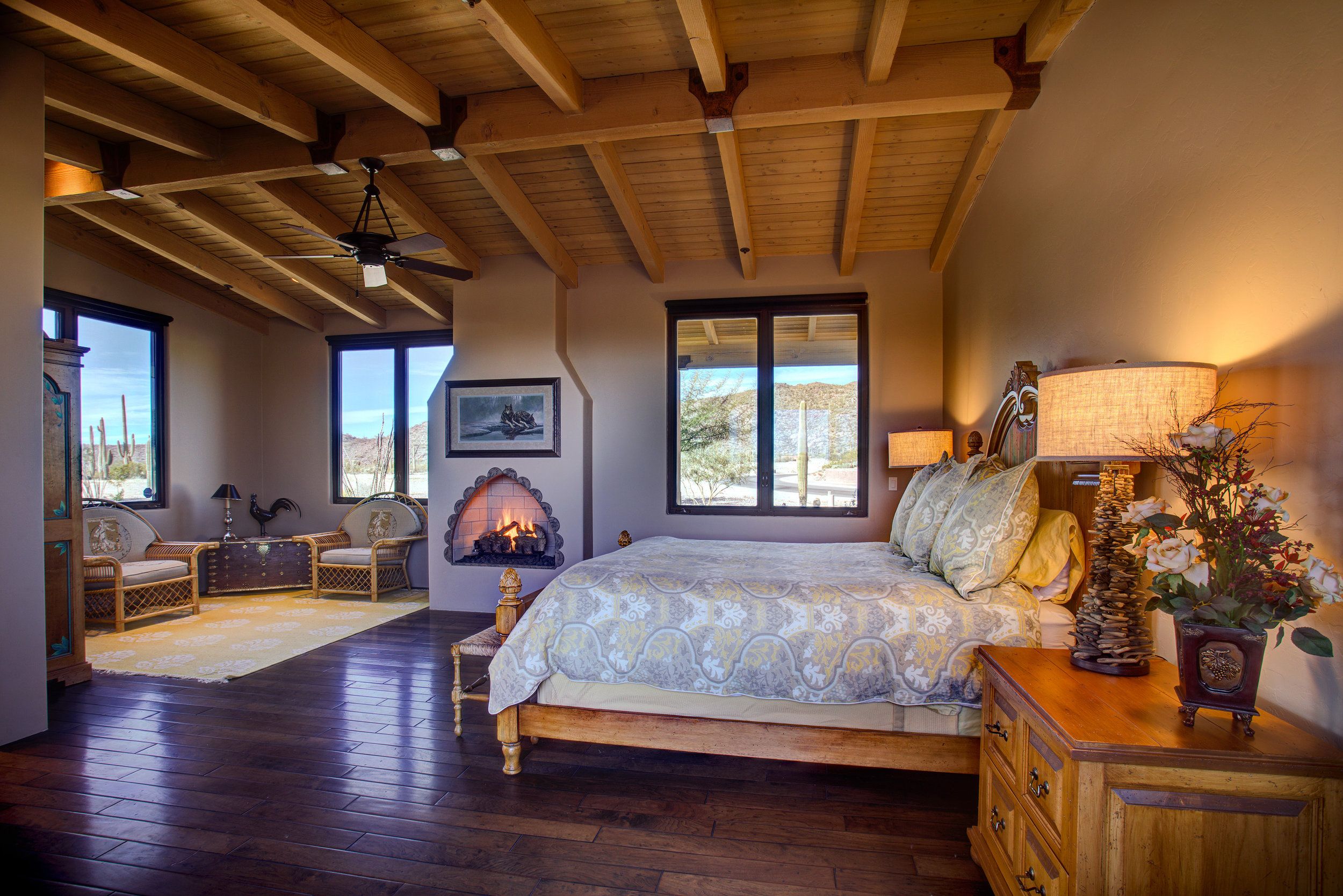 Guest bedroom with a beamed ceiling, corner kiva fireplace and windows onto the desert