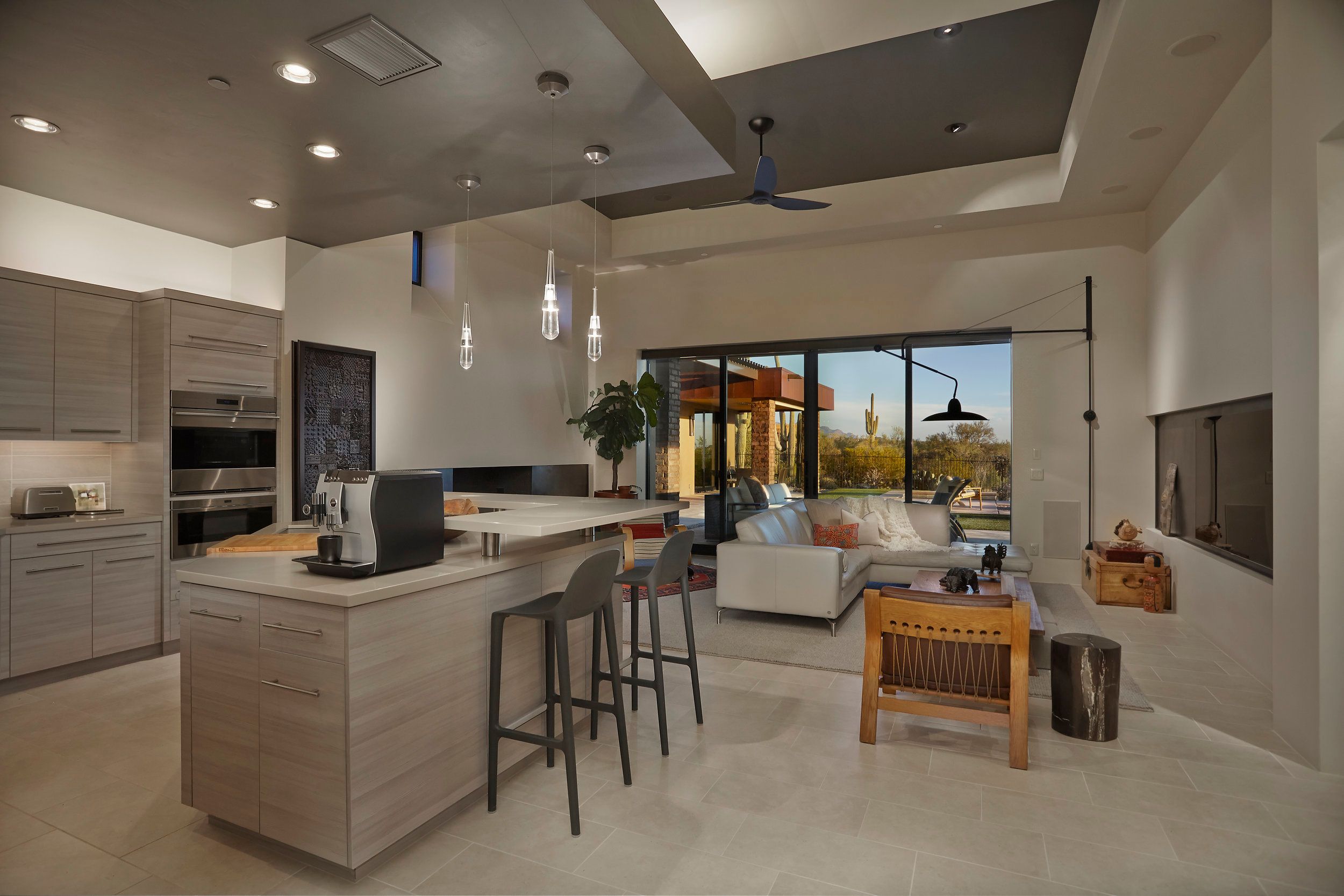 Kitchen with a white island, bar seating and a linear fireplace in the living area