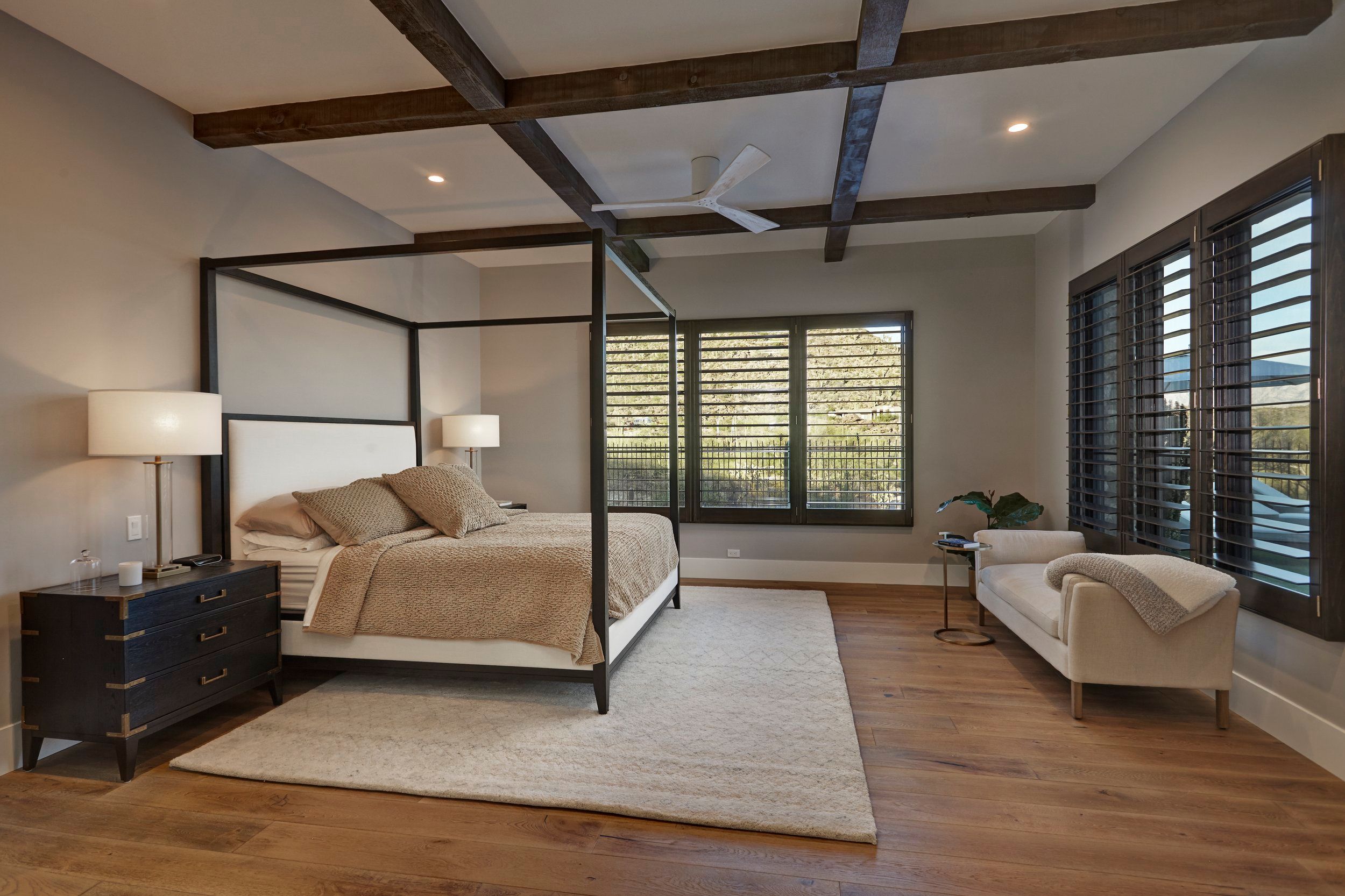 Primary bedroom with a four-poster bed, beamed ceiling and plantation shutters