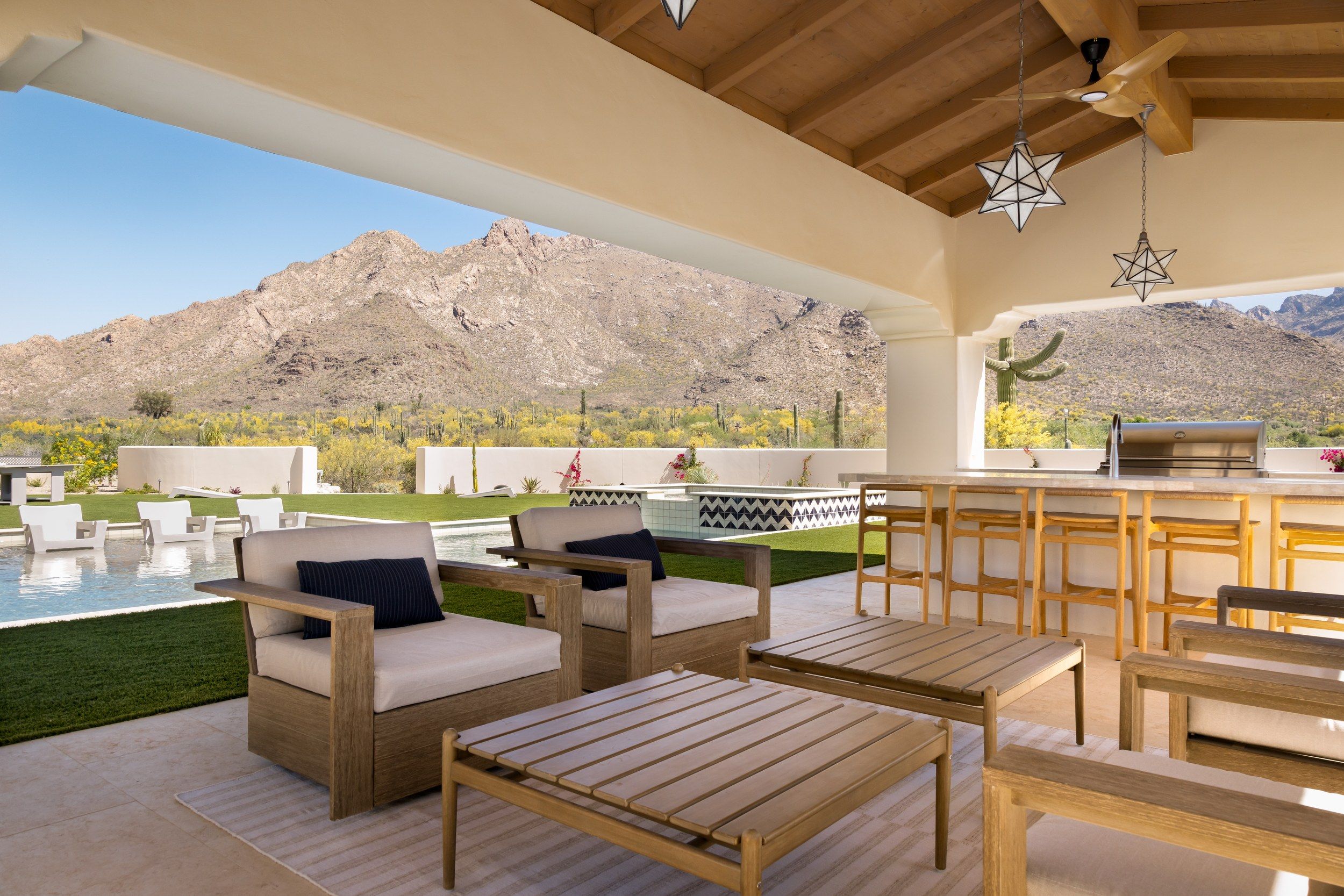 Outdoor living room under a beamed ramada looking across the pool to the mountains