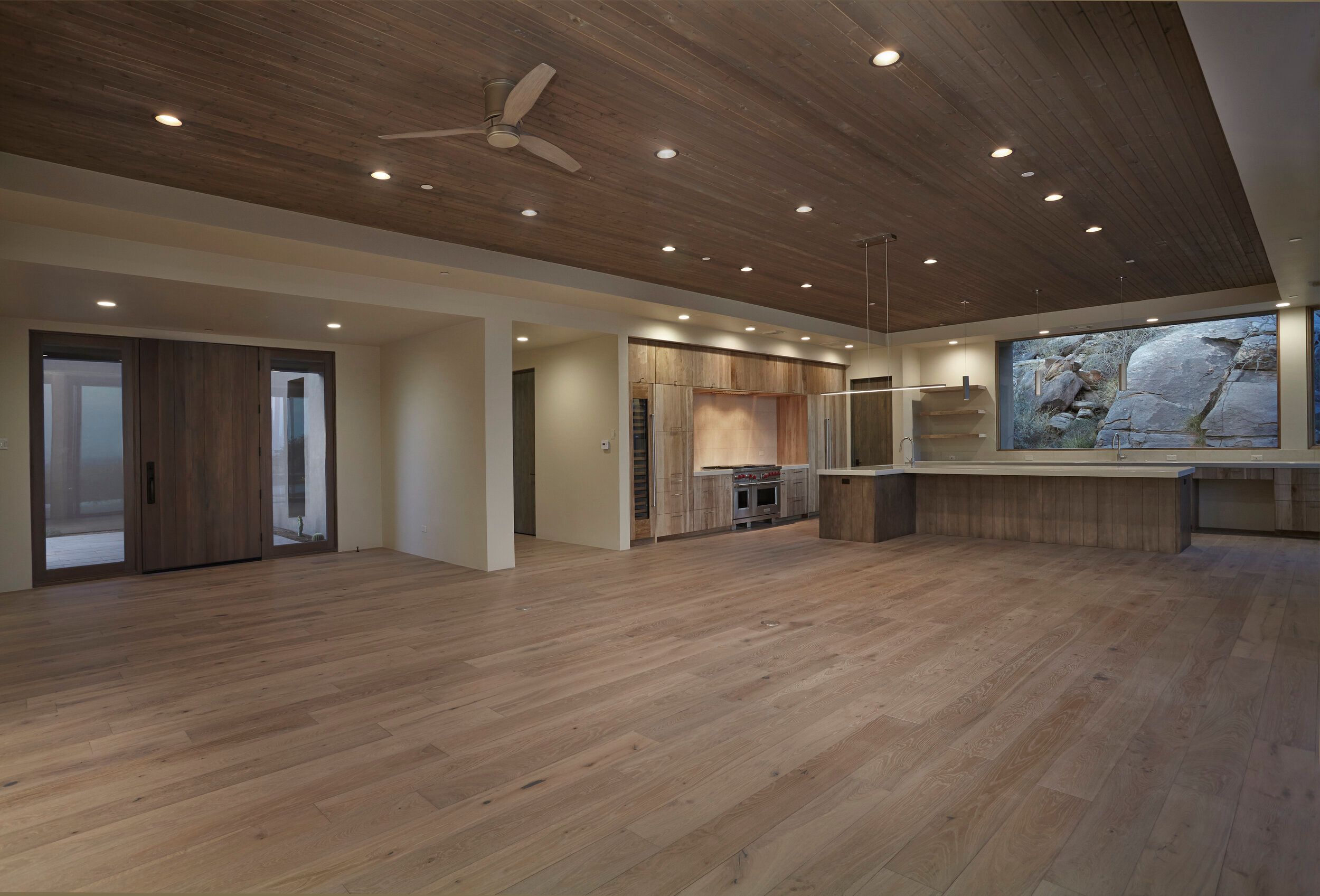 Great room looking back toward the kitchen with a boulder framed in the window