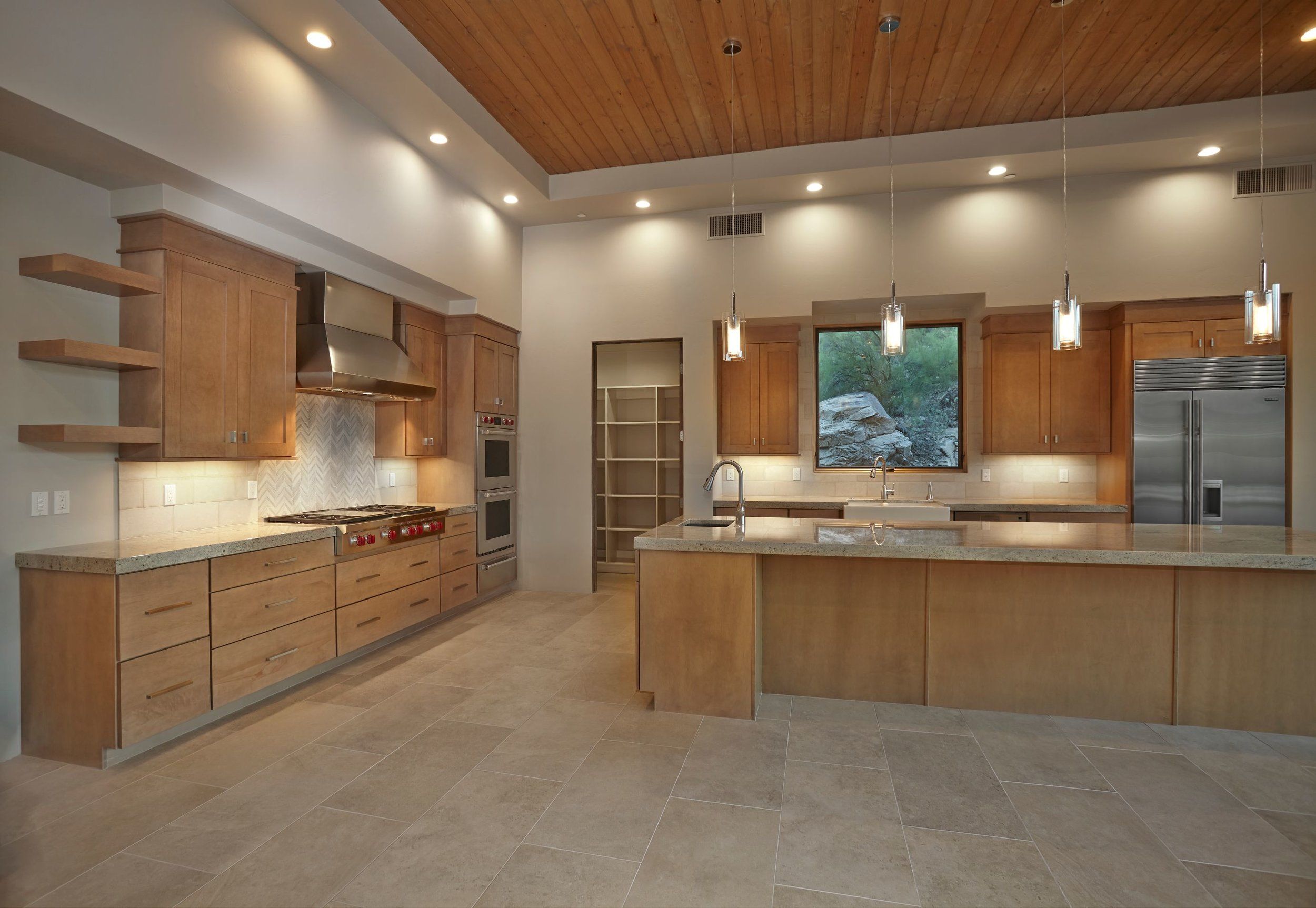 Kitchen with open shelving, a professional cooktop and island prep sink