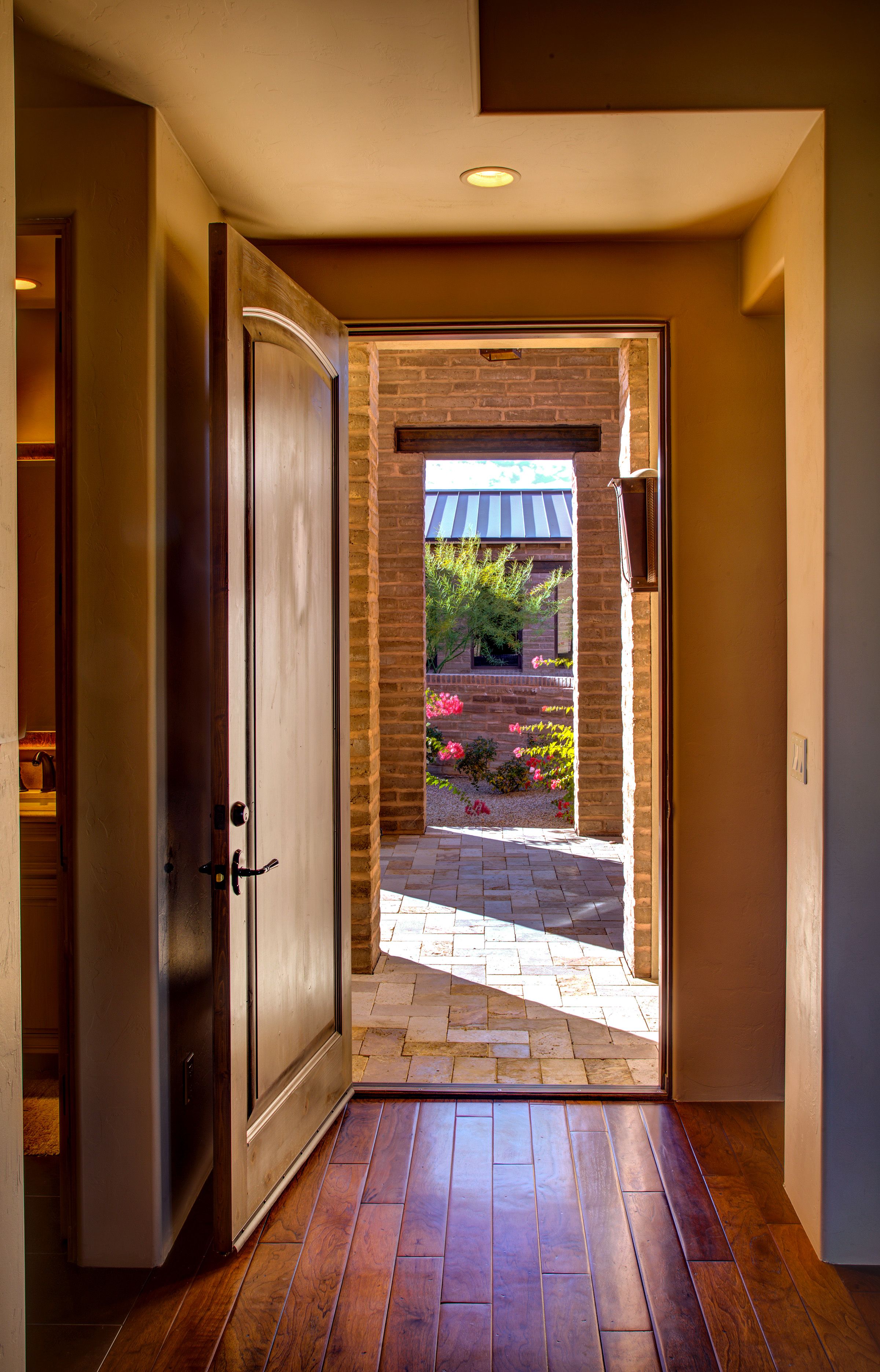 Entry hall with the front door standing open onto the paver courtyard