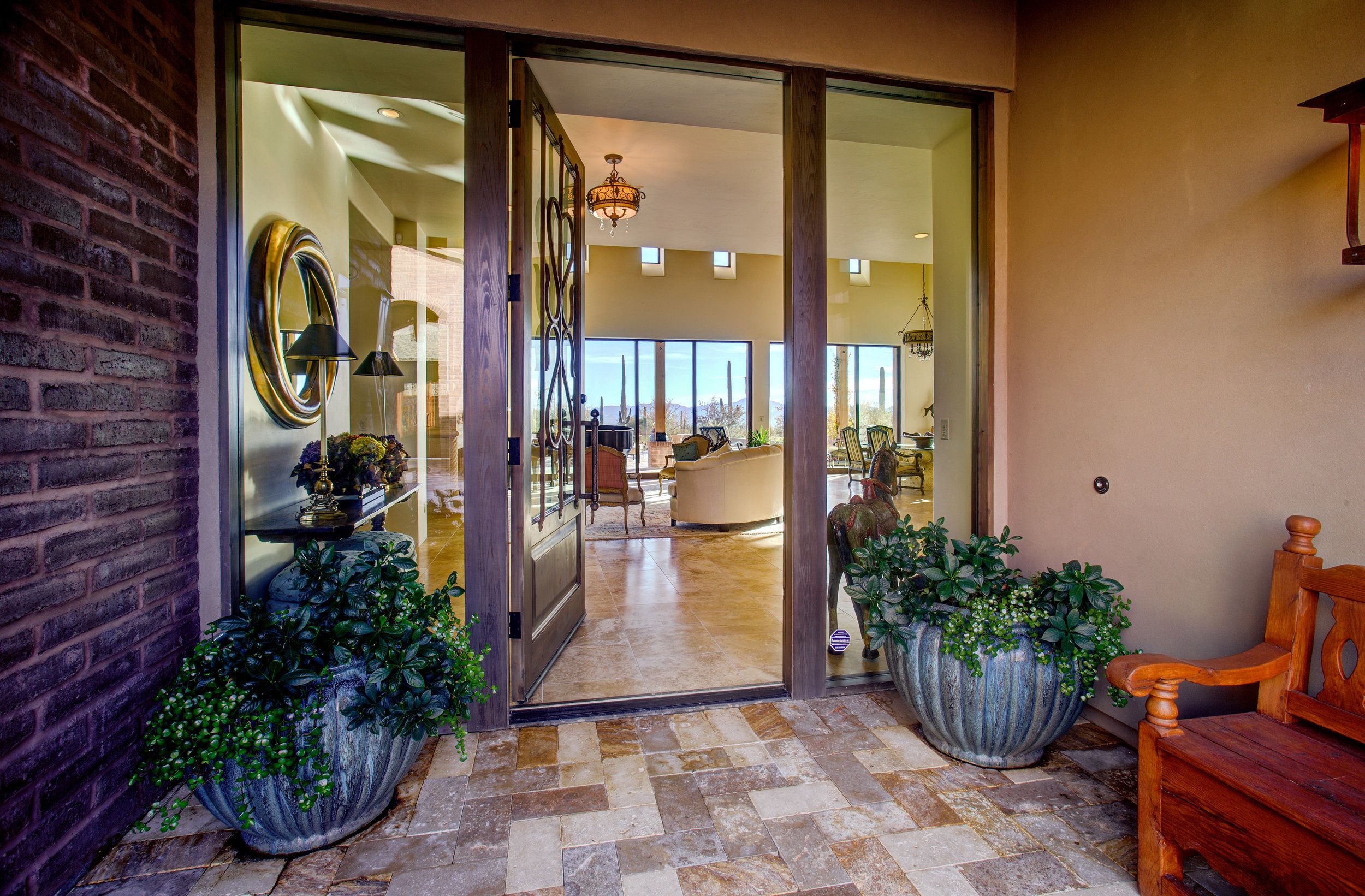 Brick-framed glass entry doors seen from the courtyard, flanked by potted plants
