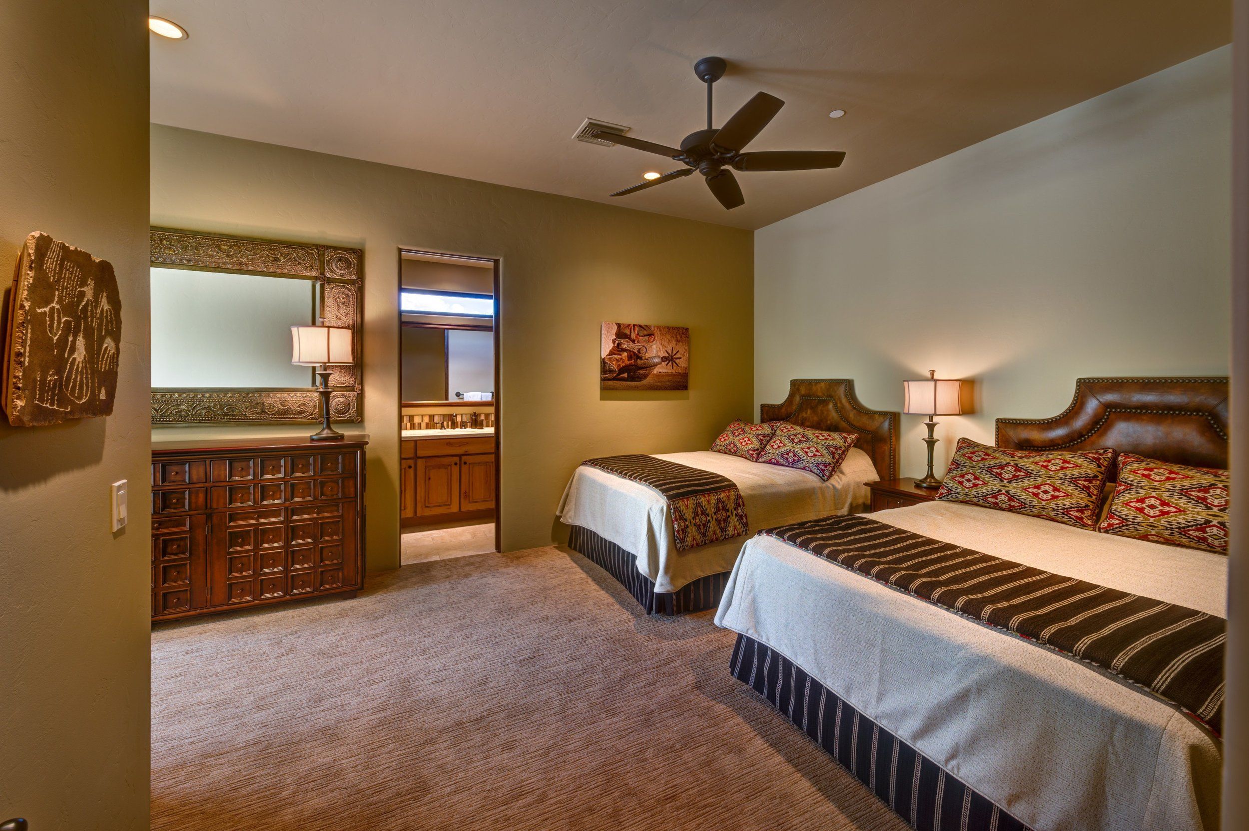 Twin-bed guest room with carved leather headboards and an ensuite beyond