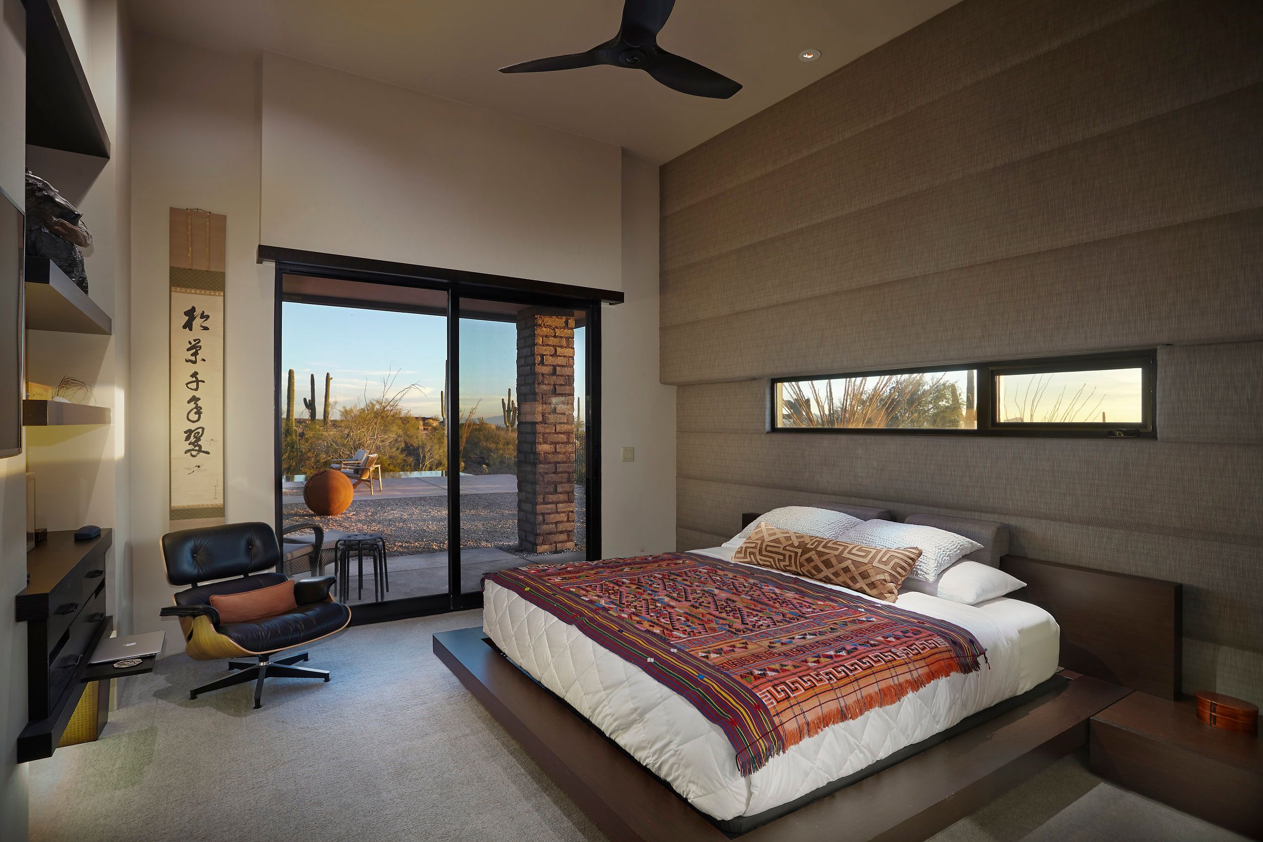 Bedroom with a platform bed, textured feature wall and sliding doors to the desert
