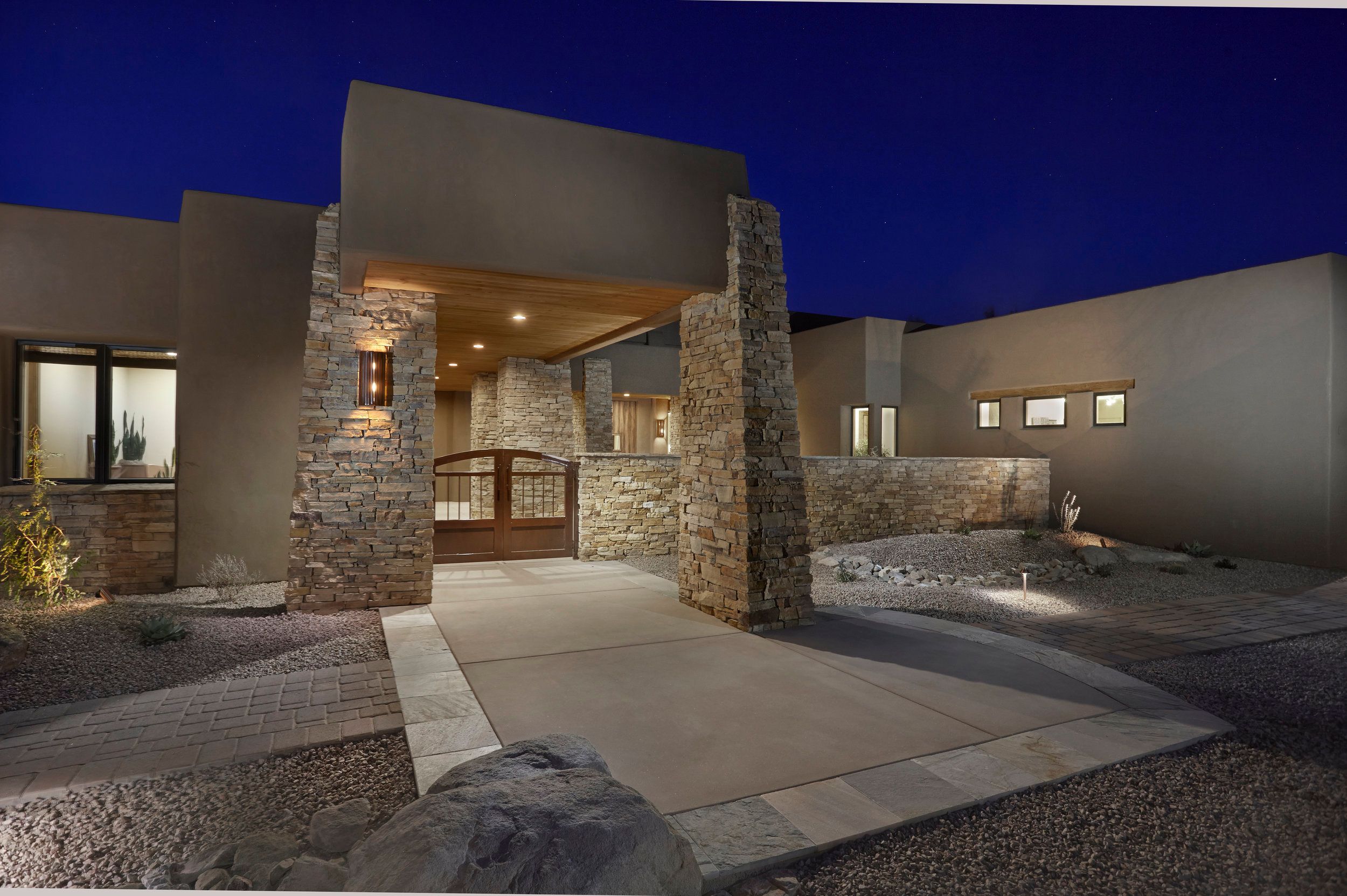 Stone-columned entry portico lit at dusk with a concrete walk