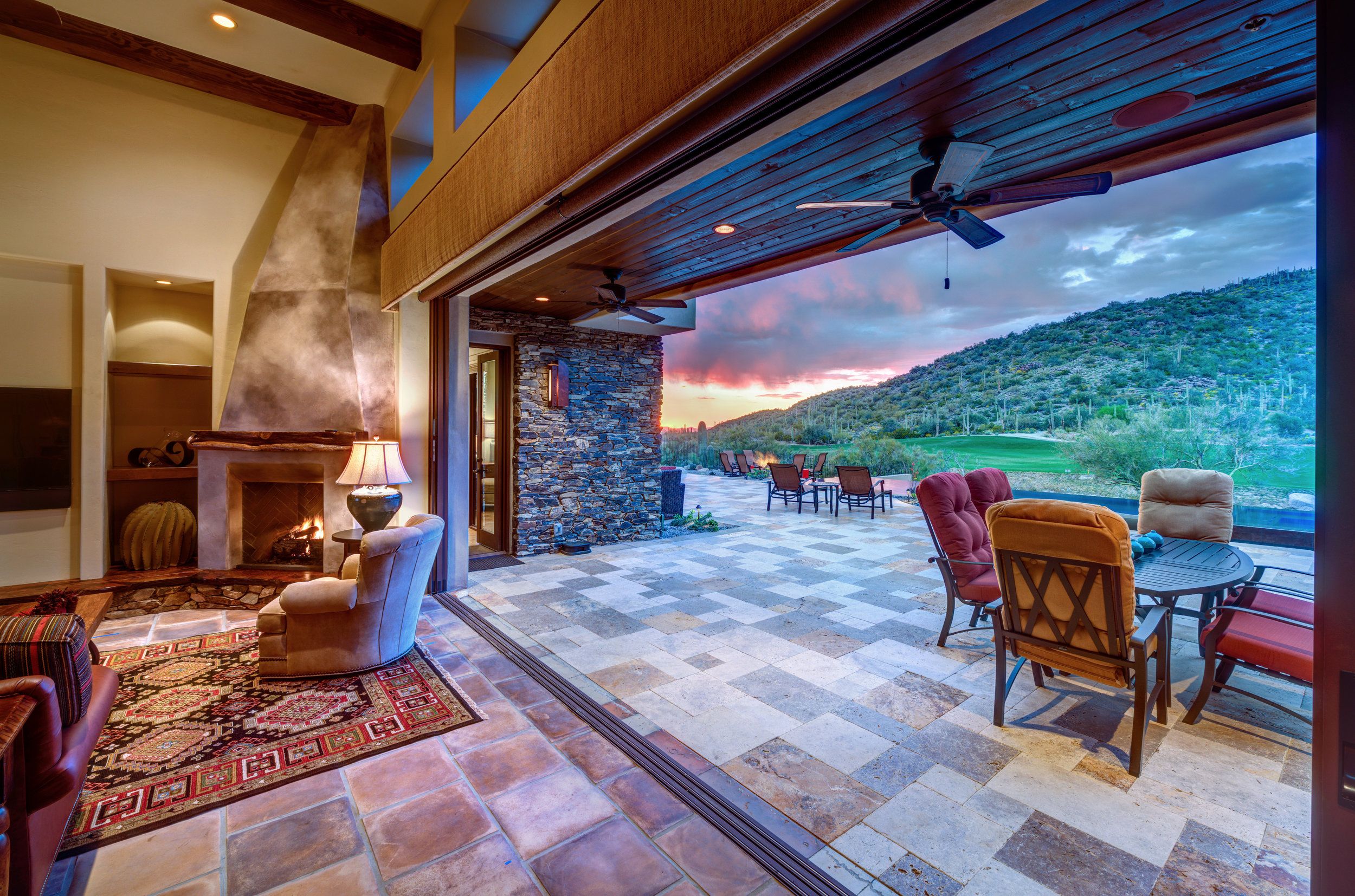 Living room opening through a retracting glass wall onto the patio at sunset