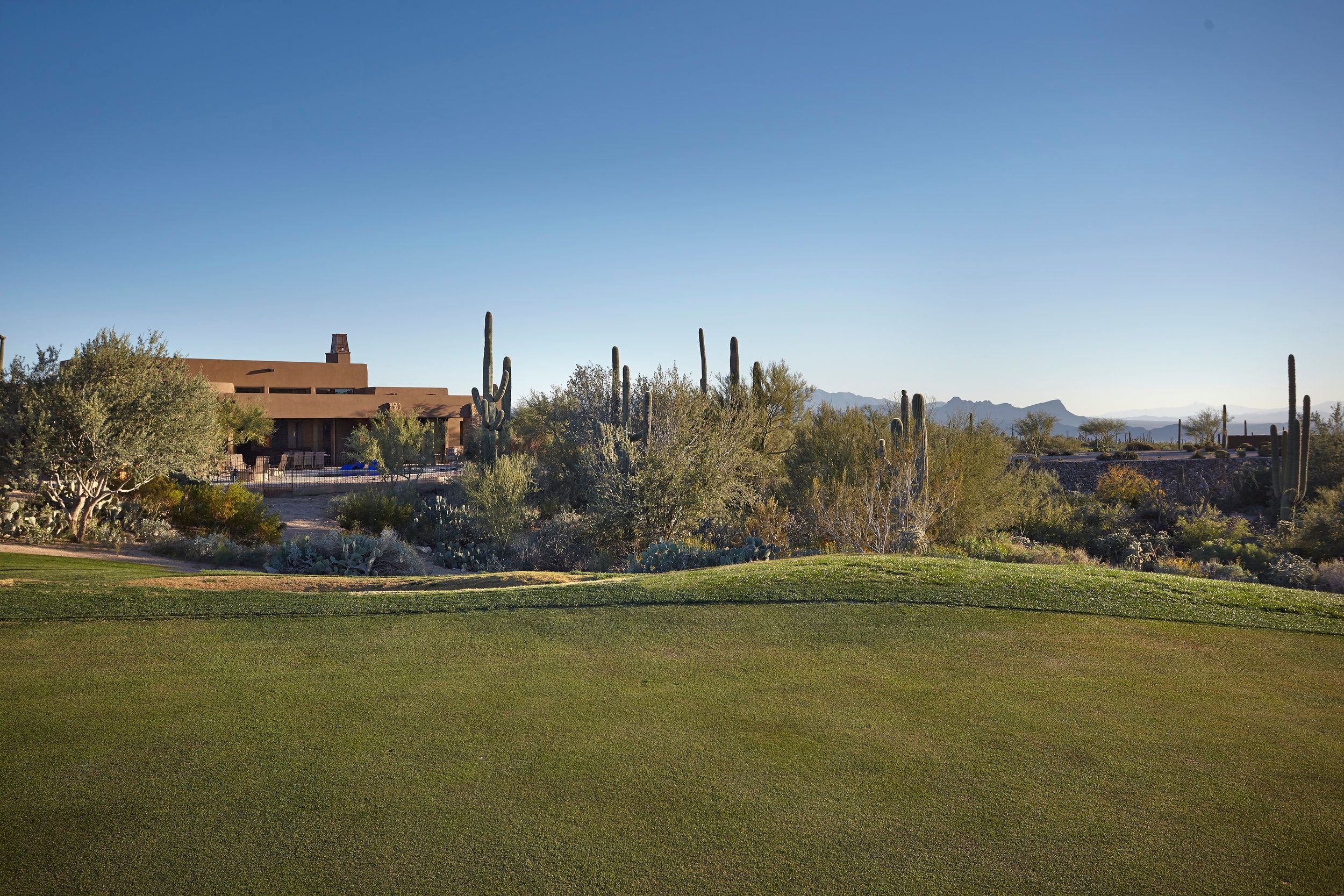 The residence seen across the golf course fairway with saguaros and mountains