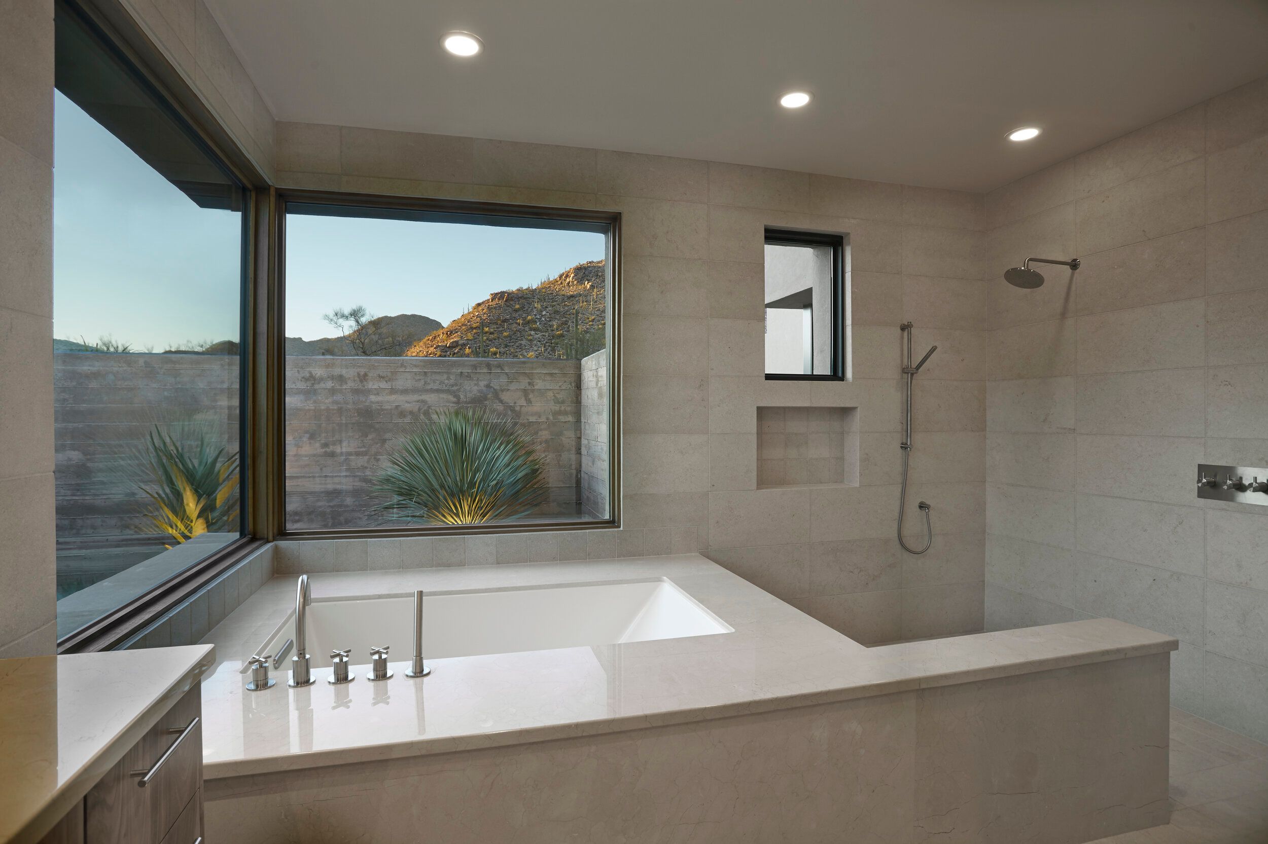 Primary bathroom with a drop-in tub beneath a corner window and walk-in shower