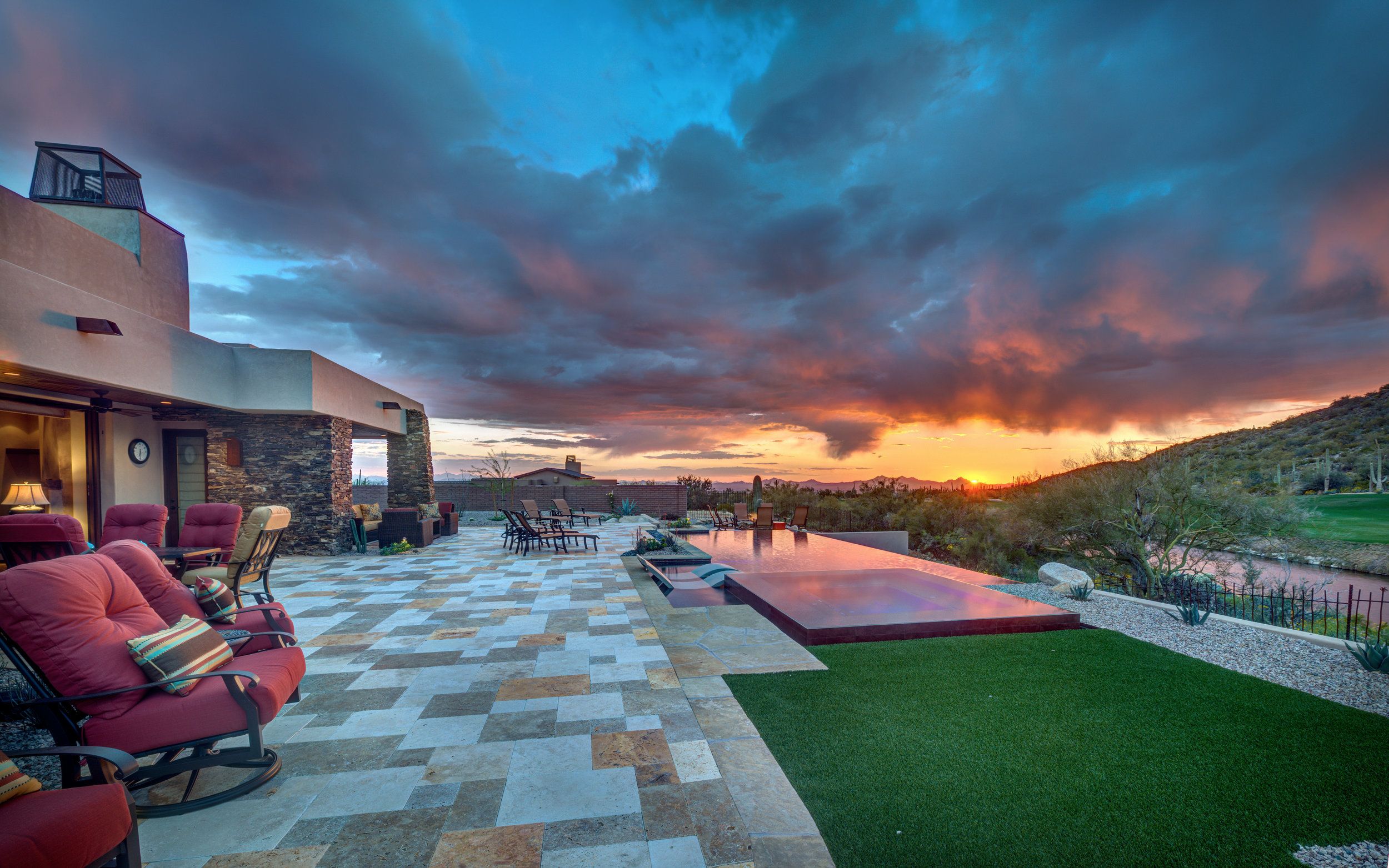 Travertine terrace and lawn at sunset with the negative-edge pool and mountains