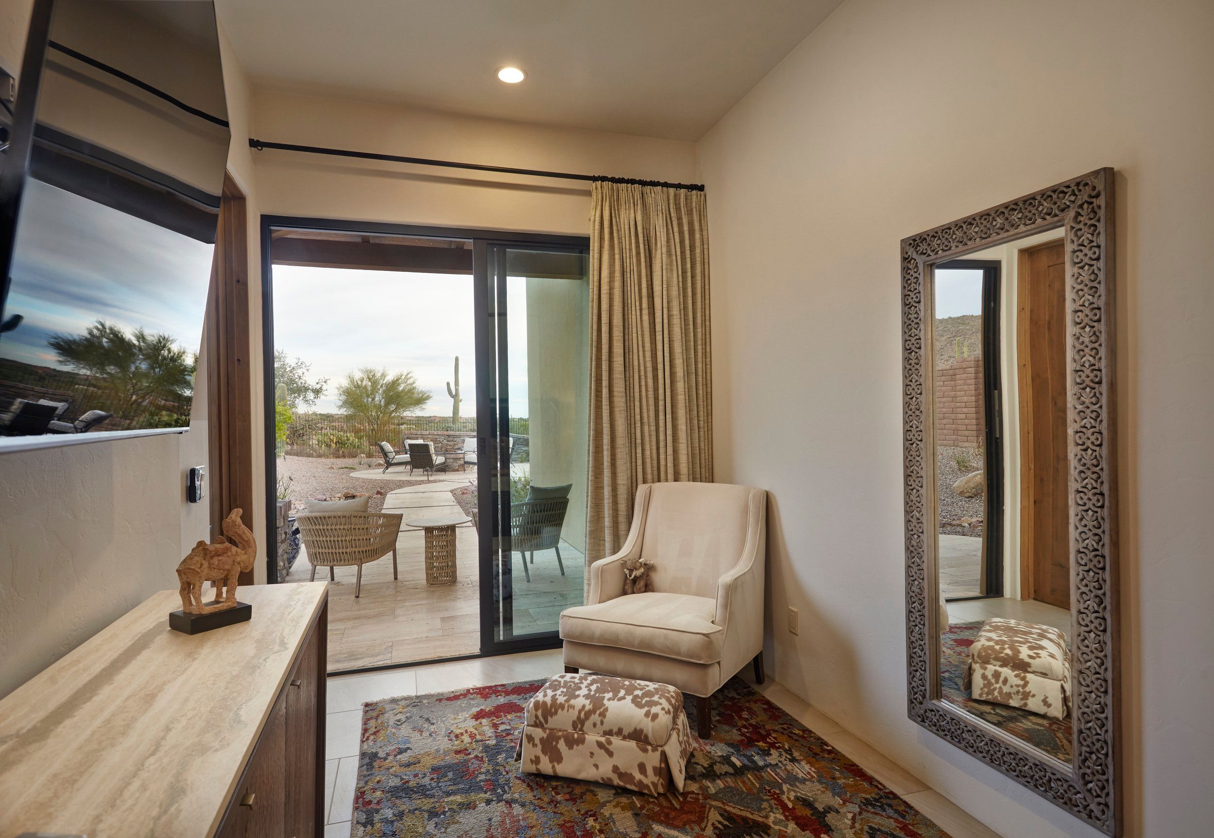 Sitting area with an armchair, ornate mirror and sliding door onto the patio