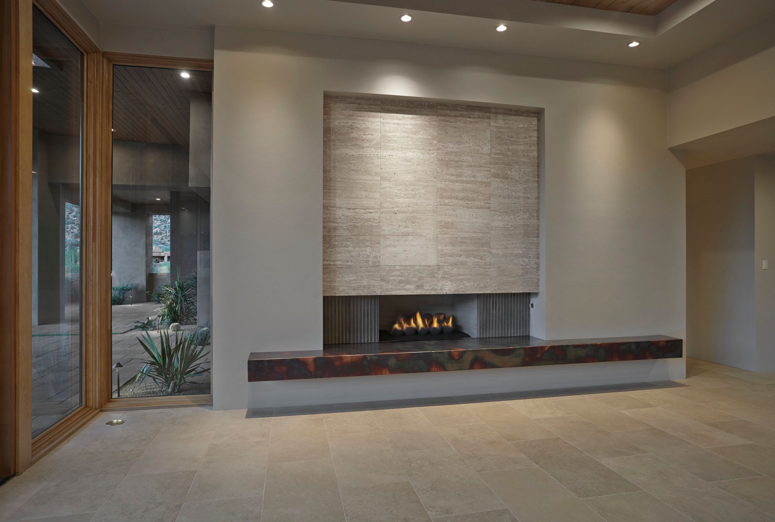 Linear gas fireplace set into a stone-clad wall with a hearth bench