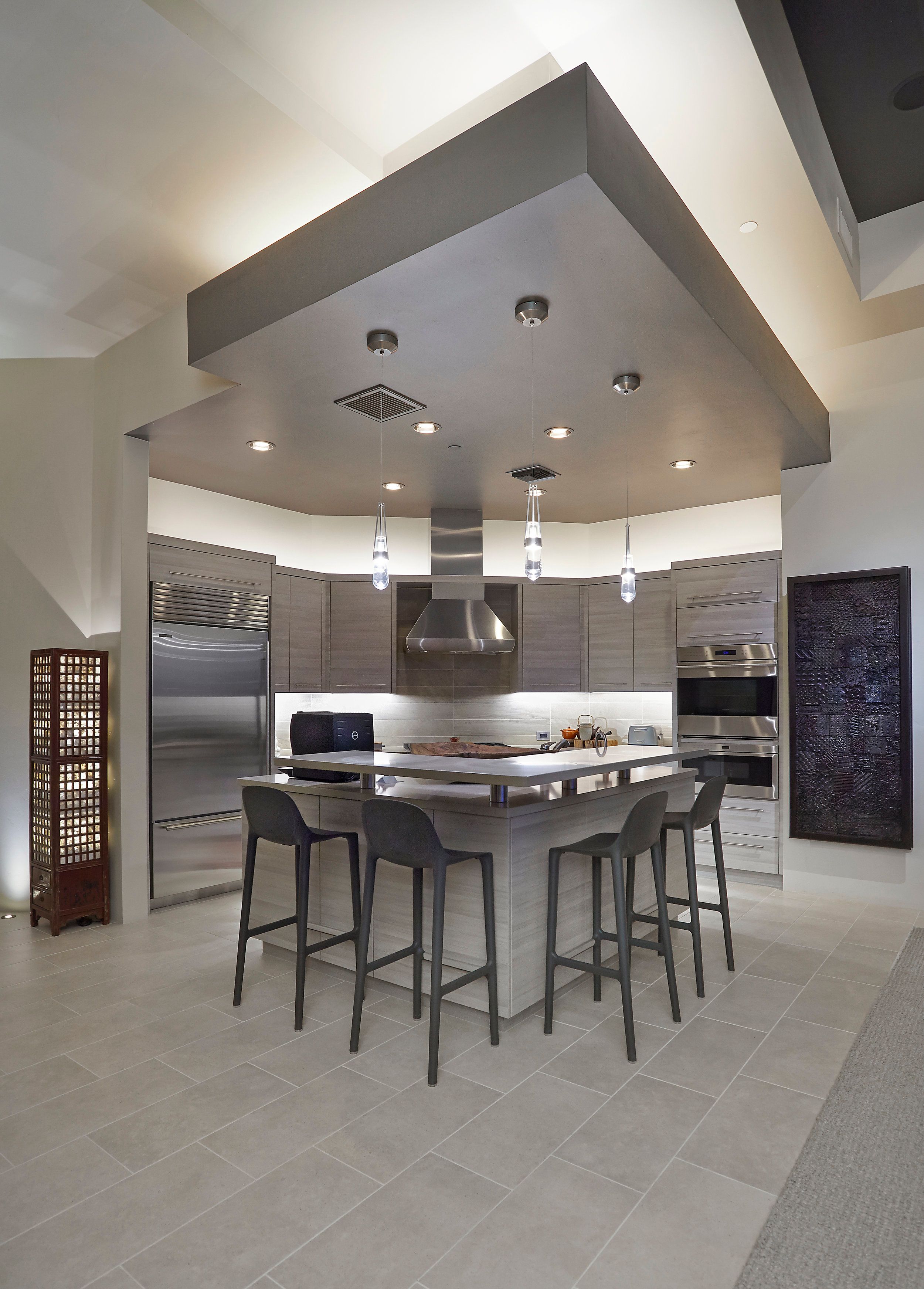 Kitchen with a stainless hood, grey cabinetry and a long island with bar stools