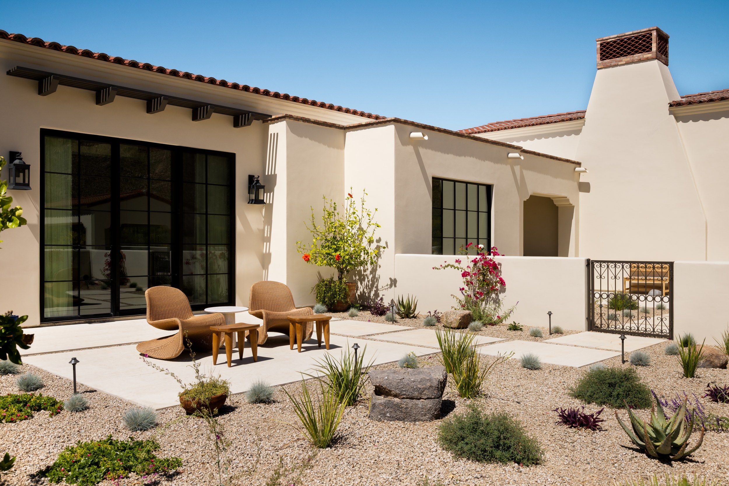 Courtyard with woven chairs, steel doors and desert plantings