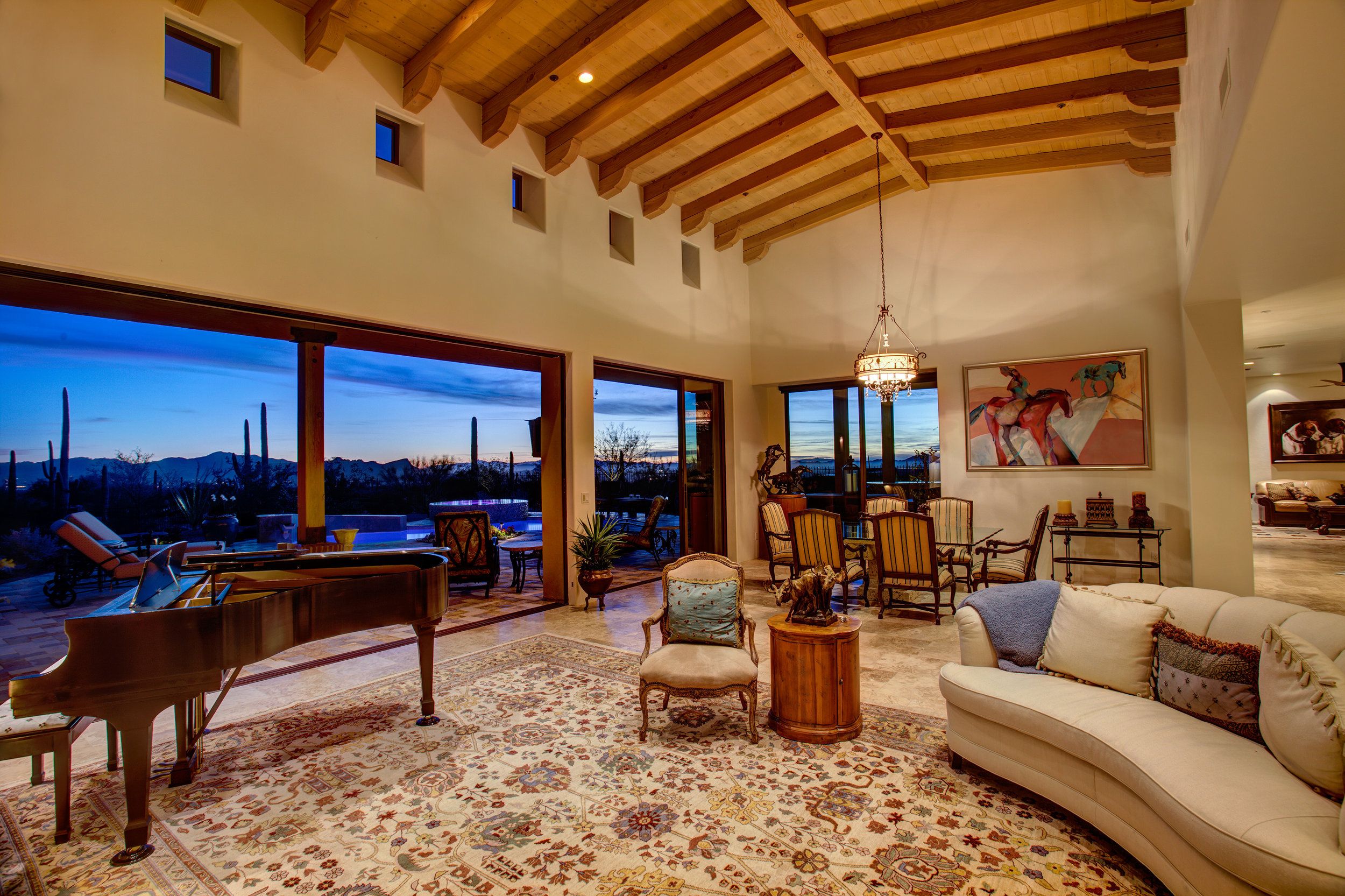 Living room at dusk with a grand piano and the pool visible through the window wall