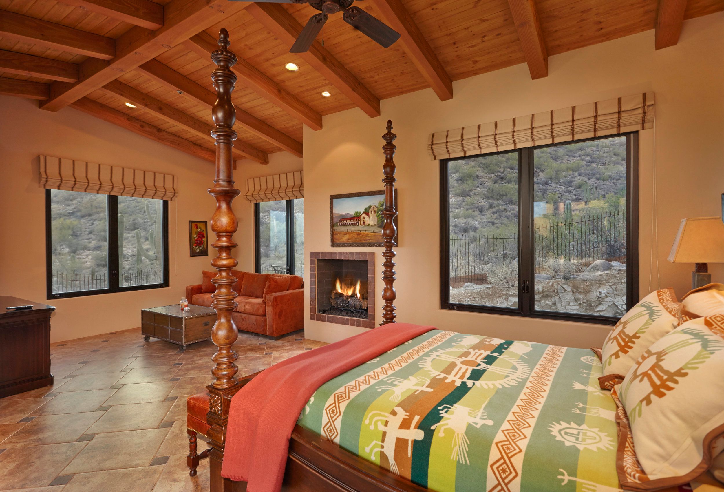 Guest bedroom with a carved four-poster bed, kiva fireplace and beamed ceiling