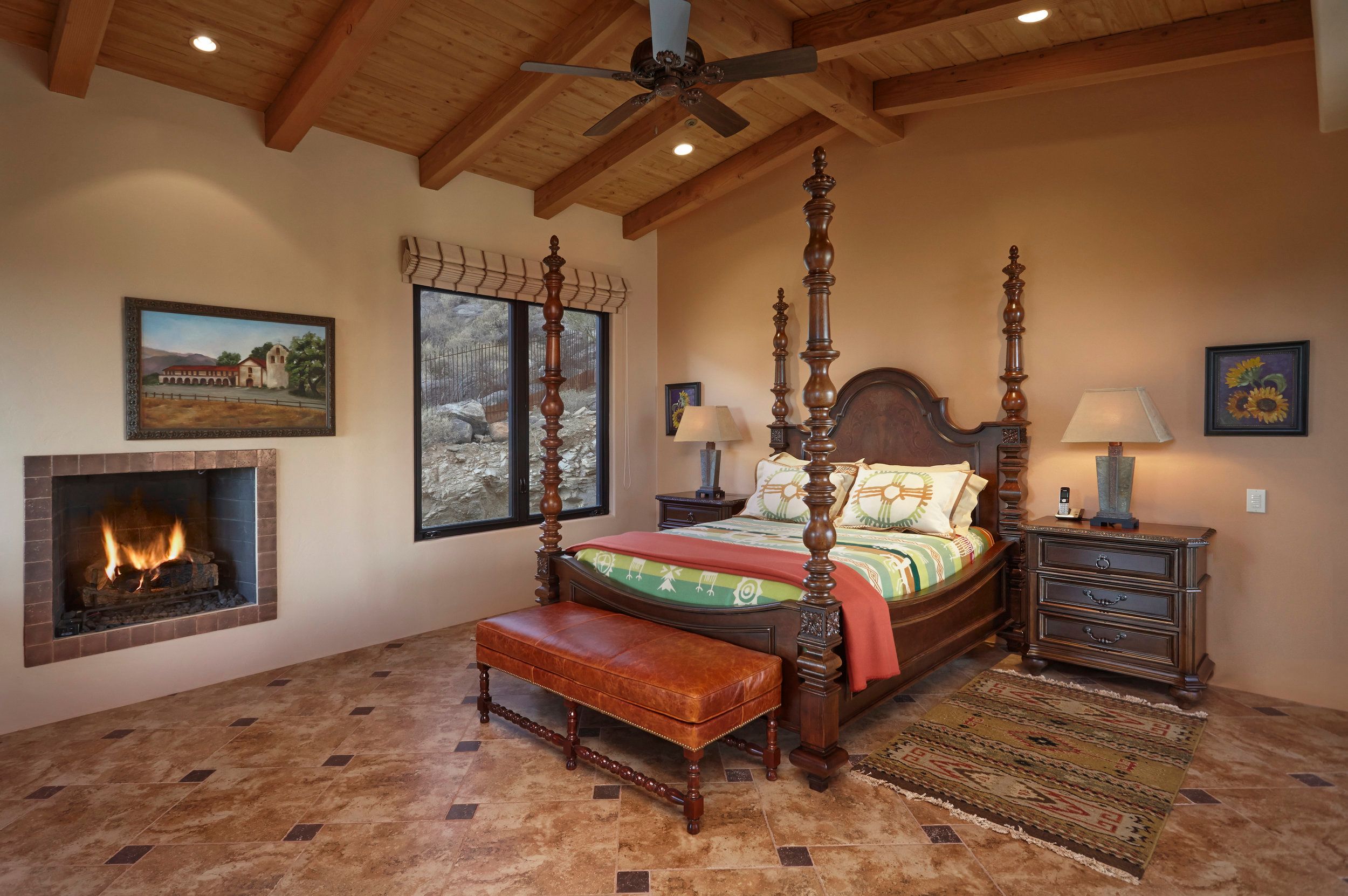 Bedroom with a carved wooden bed, corner fireplace and leather bench