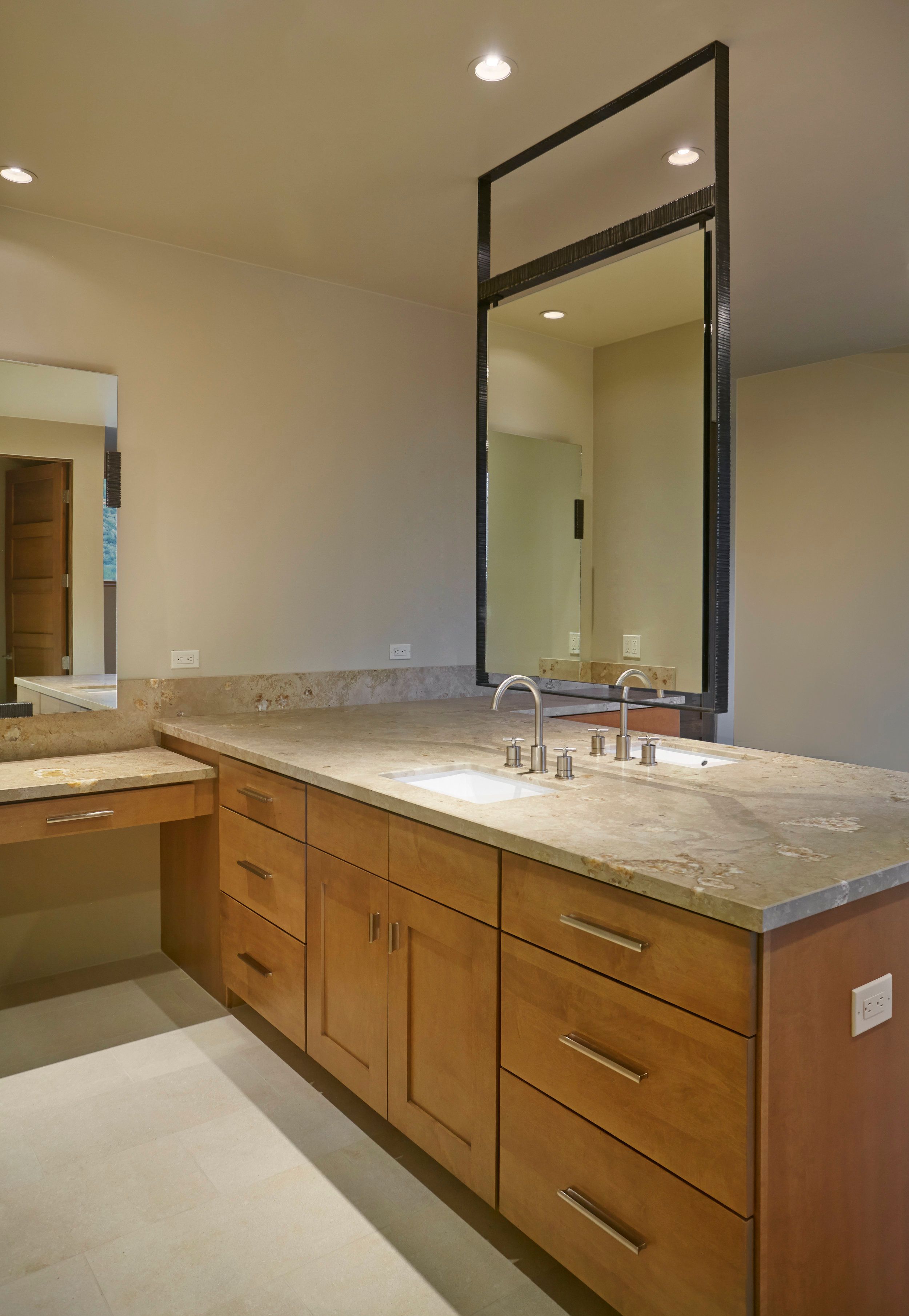 Primary vanity with a stone counter, tall mirror and integrated make-up table